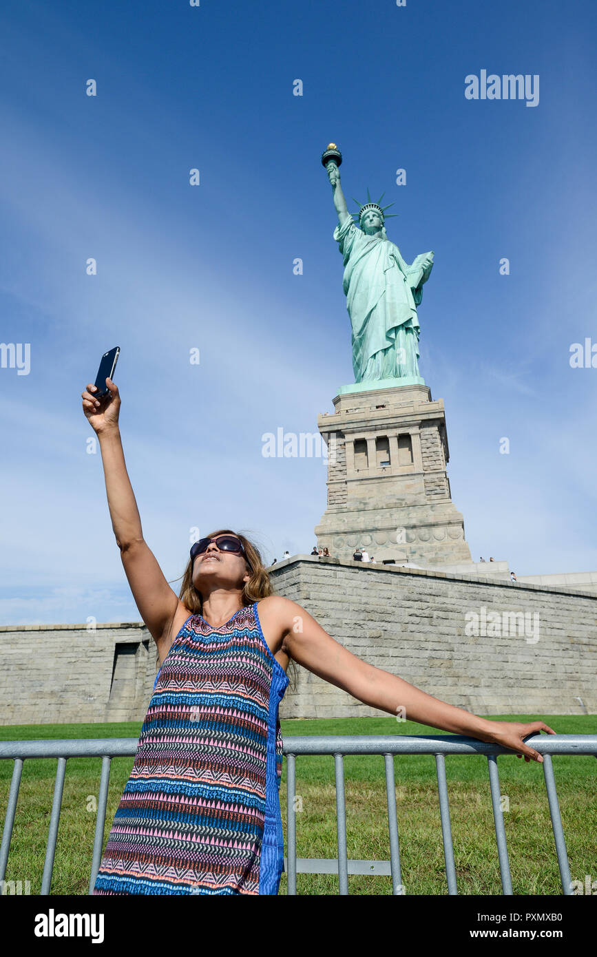 New York City, statue of liberty, woman lift up the apple iphone to take a  selfie Stock Photo - Alamy