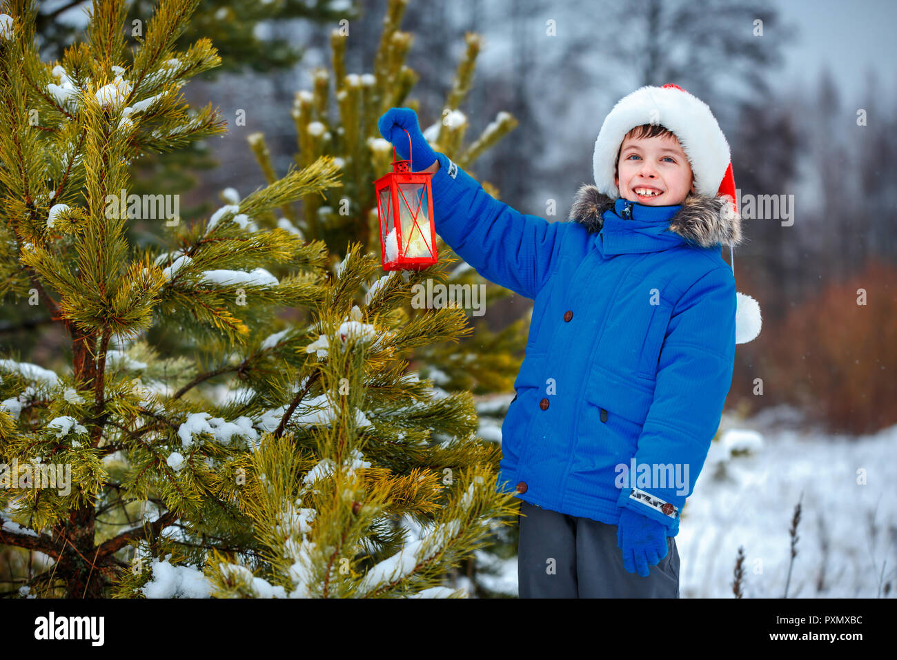 Cute little boy holding Christmas lantern outdoors on winter snow day Stock Photo