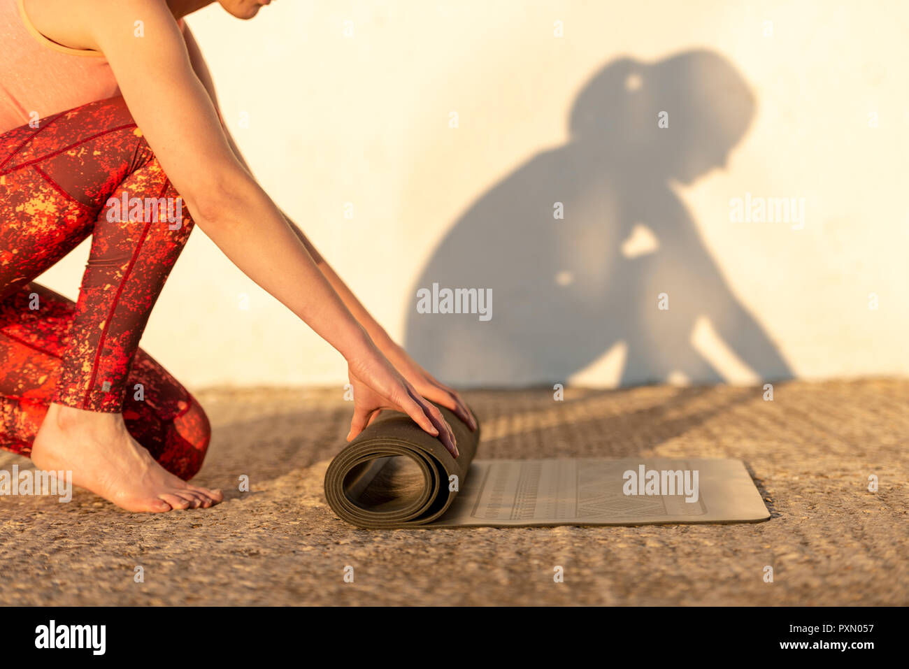 woman unrolling her yoga mat outside in the sun, close up Stock Photo