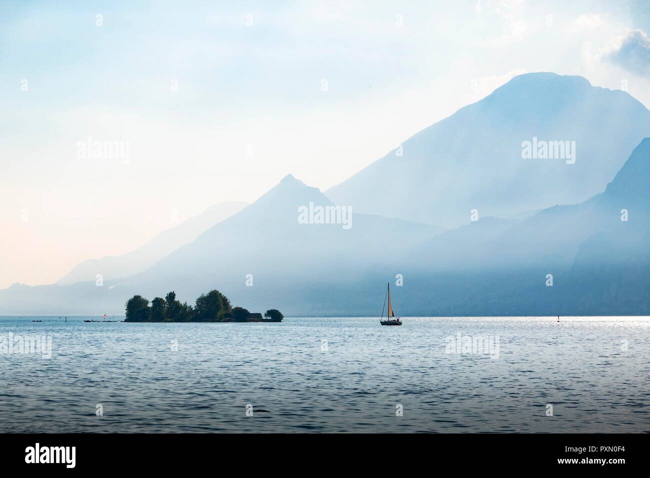 sailingbaot approachin the island of Trimelone in Lake Garda Italy  in a misty evenig light Stock Photo