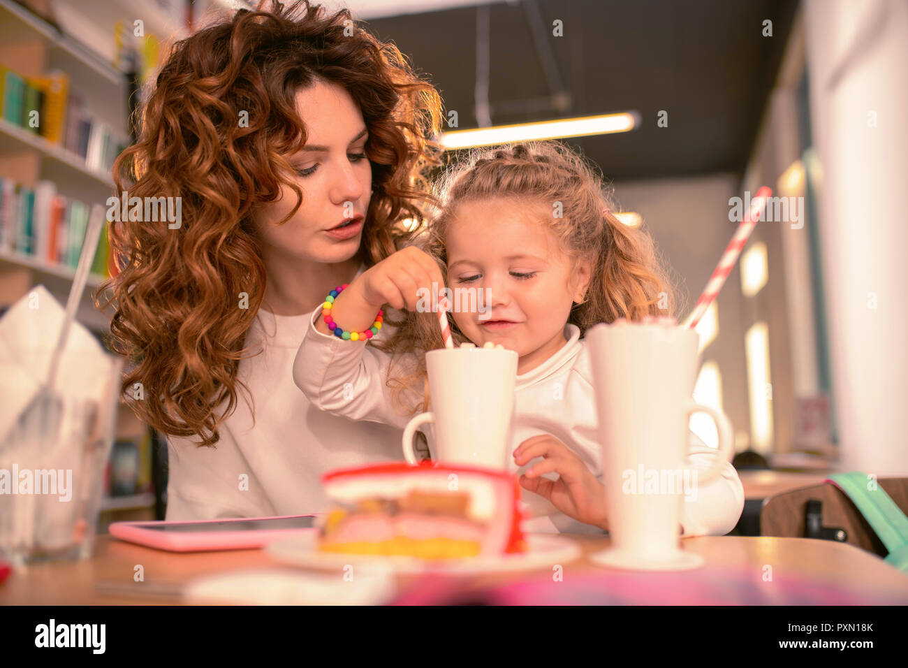 Attentive little girl mixing her cacao in glass Stock Photo