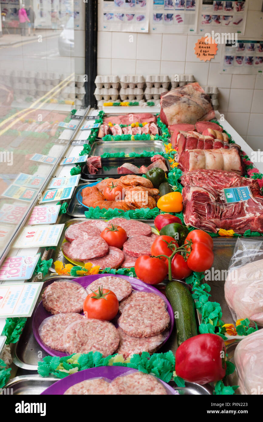 Butchers shop window with various raw joints of meats on display. England, UK Stock Photo