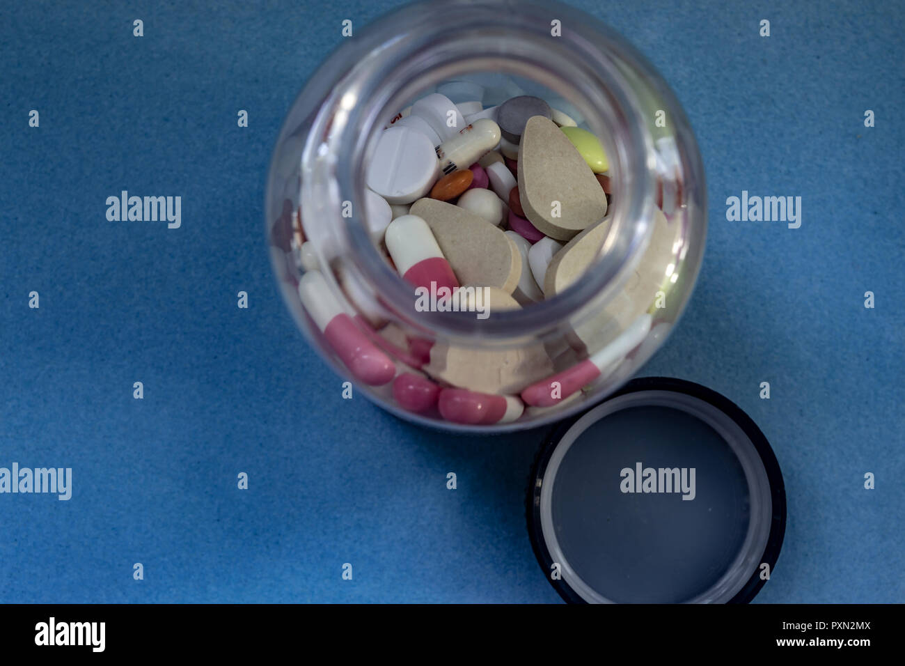 different pills in a bottle on blue background Stock Photo