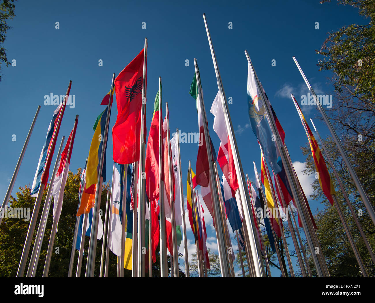 Several flagpoles with different flags in the wind before blue sky as background Stock Photo