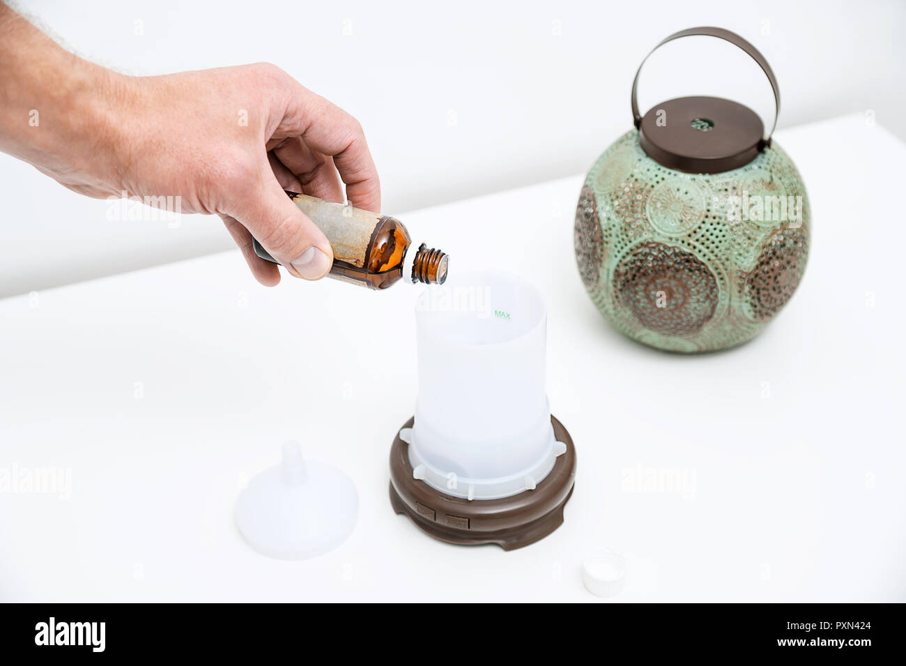 The man's hand is filling with water a capacity of aroma diffuser Stock