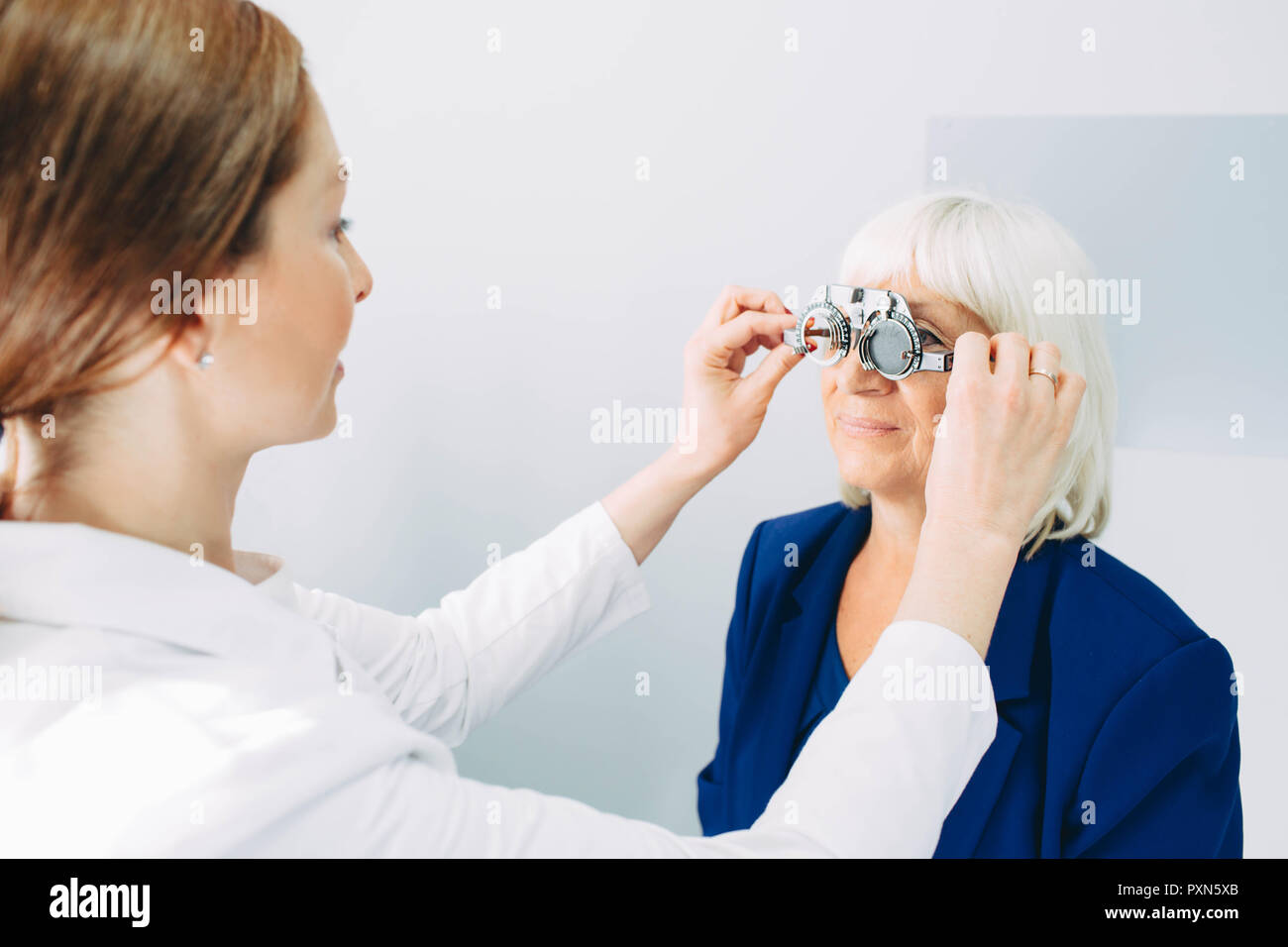 Optician doctor examining old woman's eye, using a trial frame Stock Photo