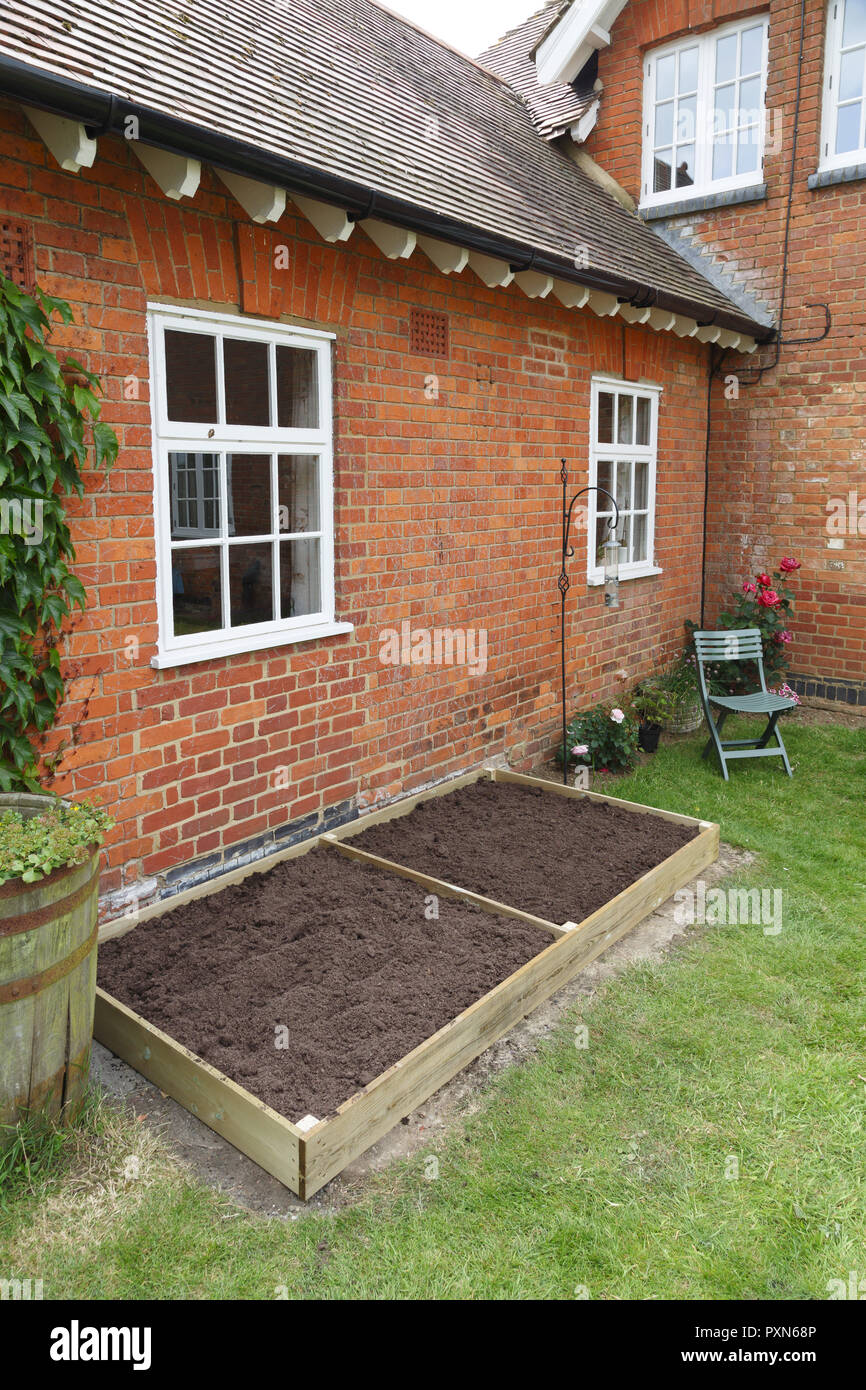 A new empty raised bed in a kitchen garden is filled with soil ready to plant Stock Photo