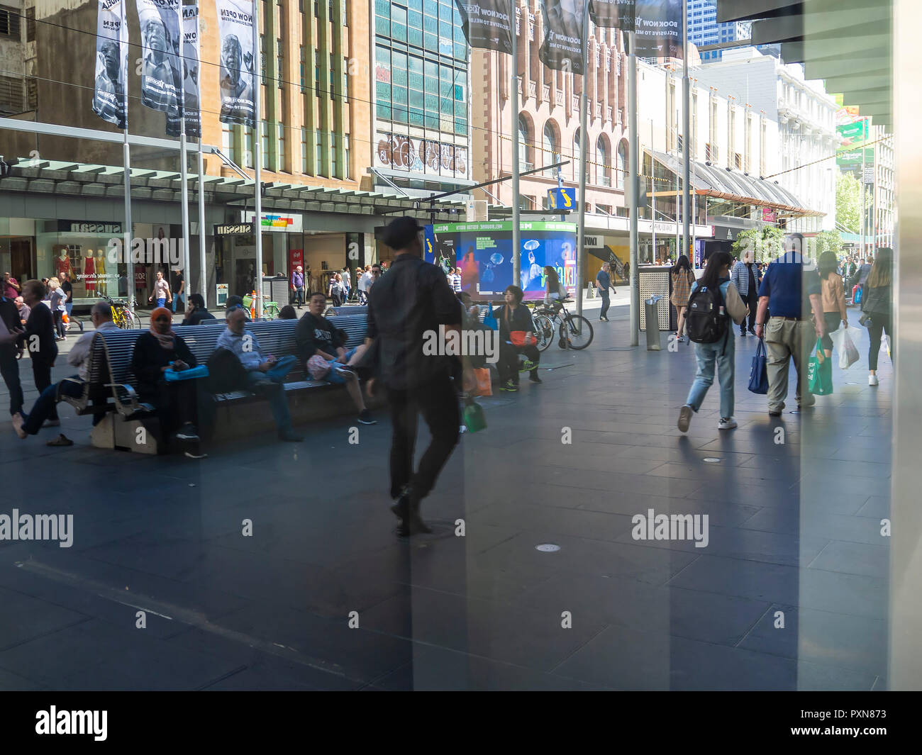 A moment in time captured in a city as reflections of multiple people going about their life are seen in a distorted view in a shop window Stock Photo