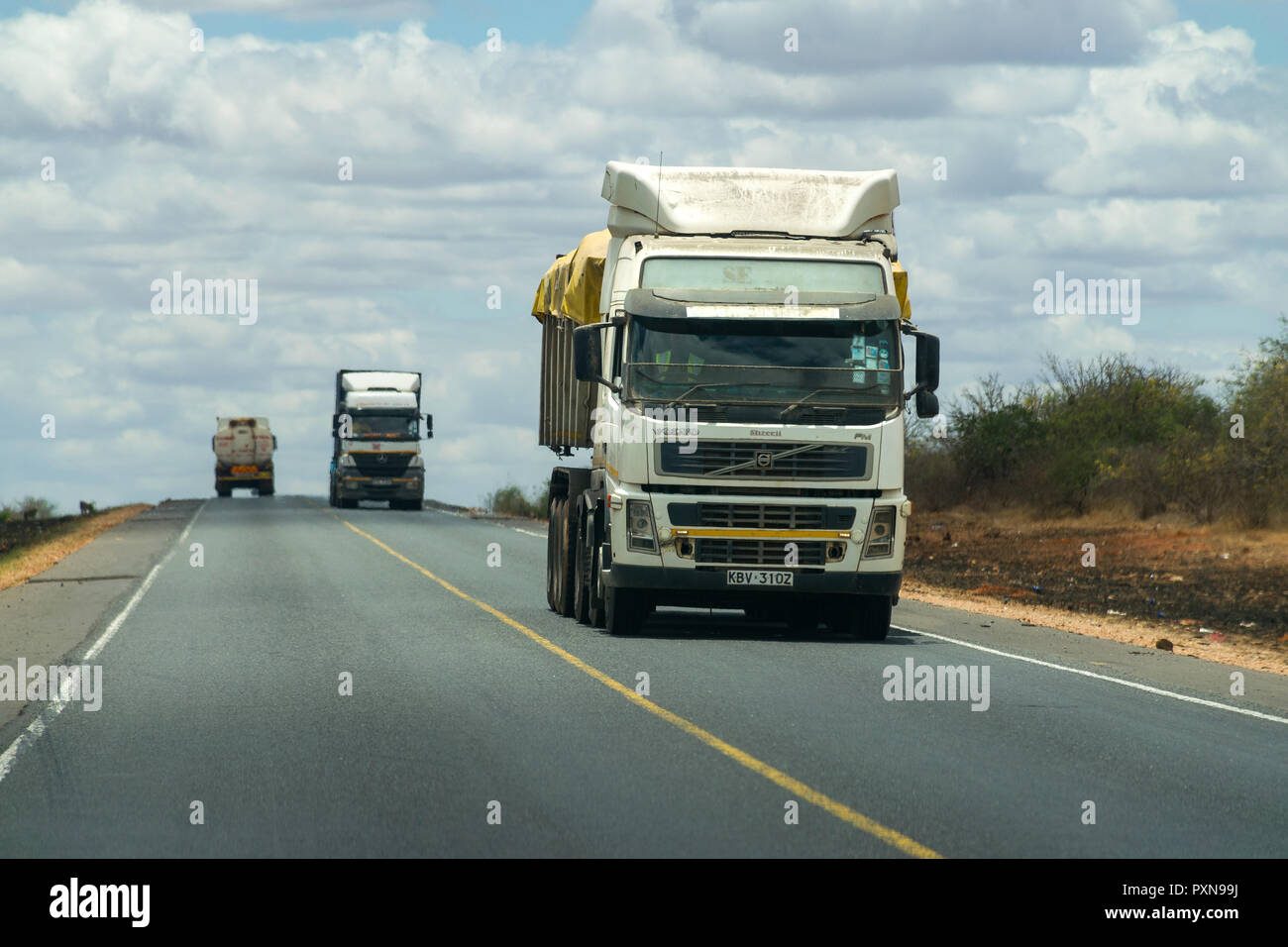 Trucks and lorries transporting goods along Mombasa to Nairobi road on a sunny day, Kenya Stock Photo