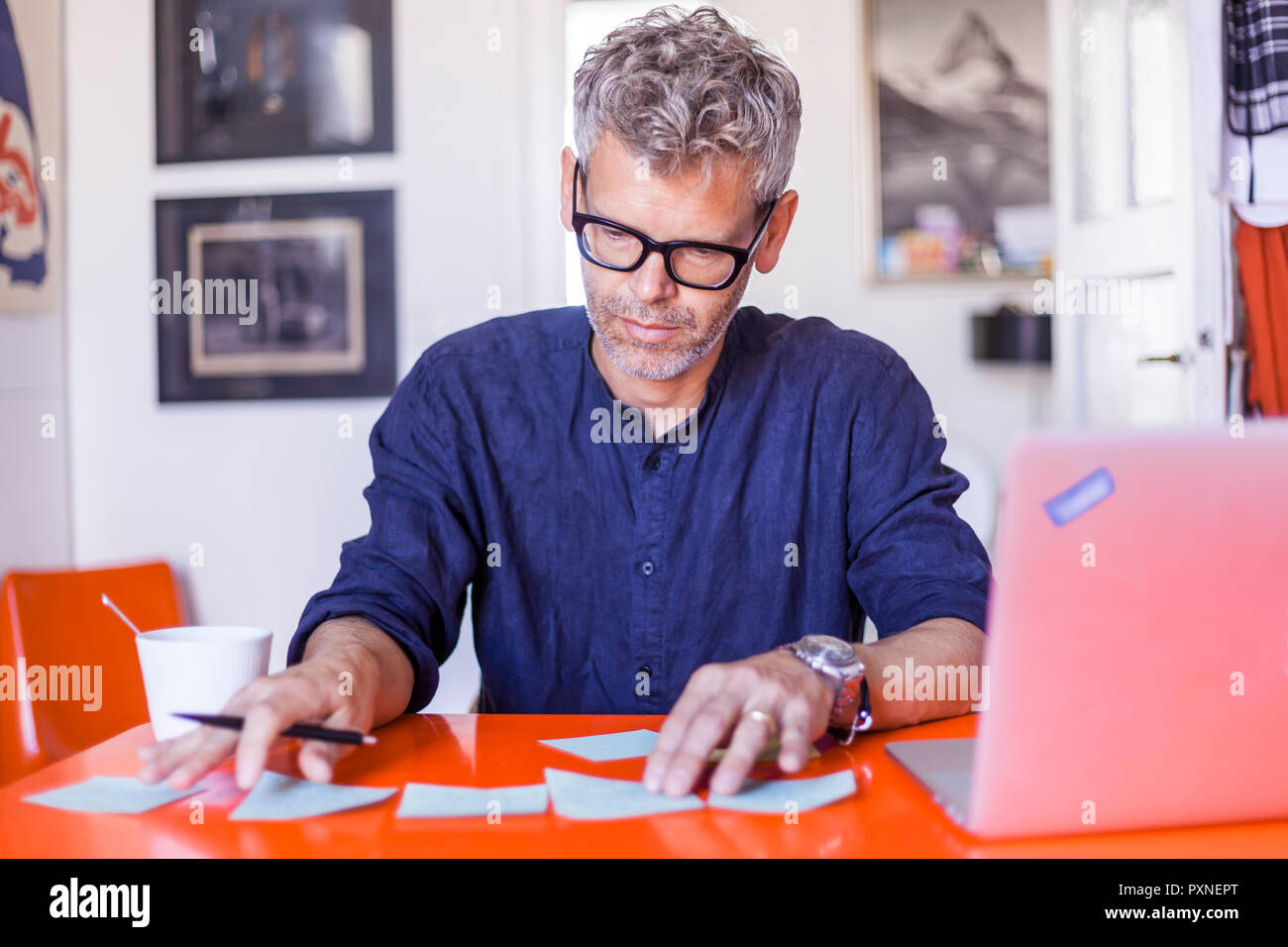 Mature man with notepads and laptop on table at home Stock Photo