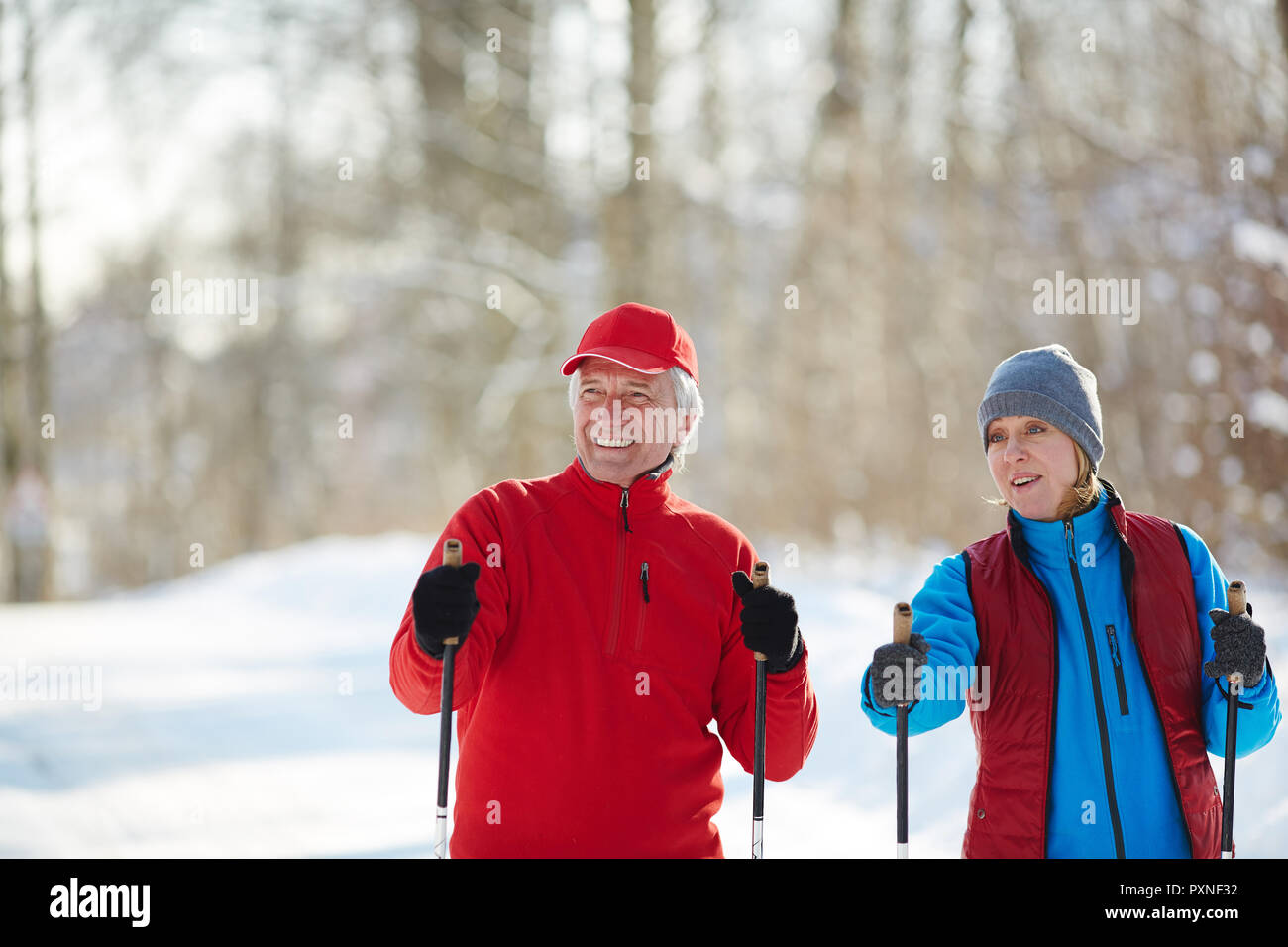 Happy mature couple in winter activewear trekking or skiing in the forest at leisure Stock Photo