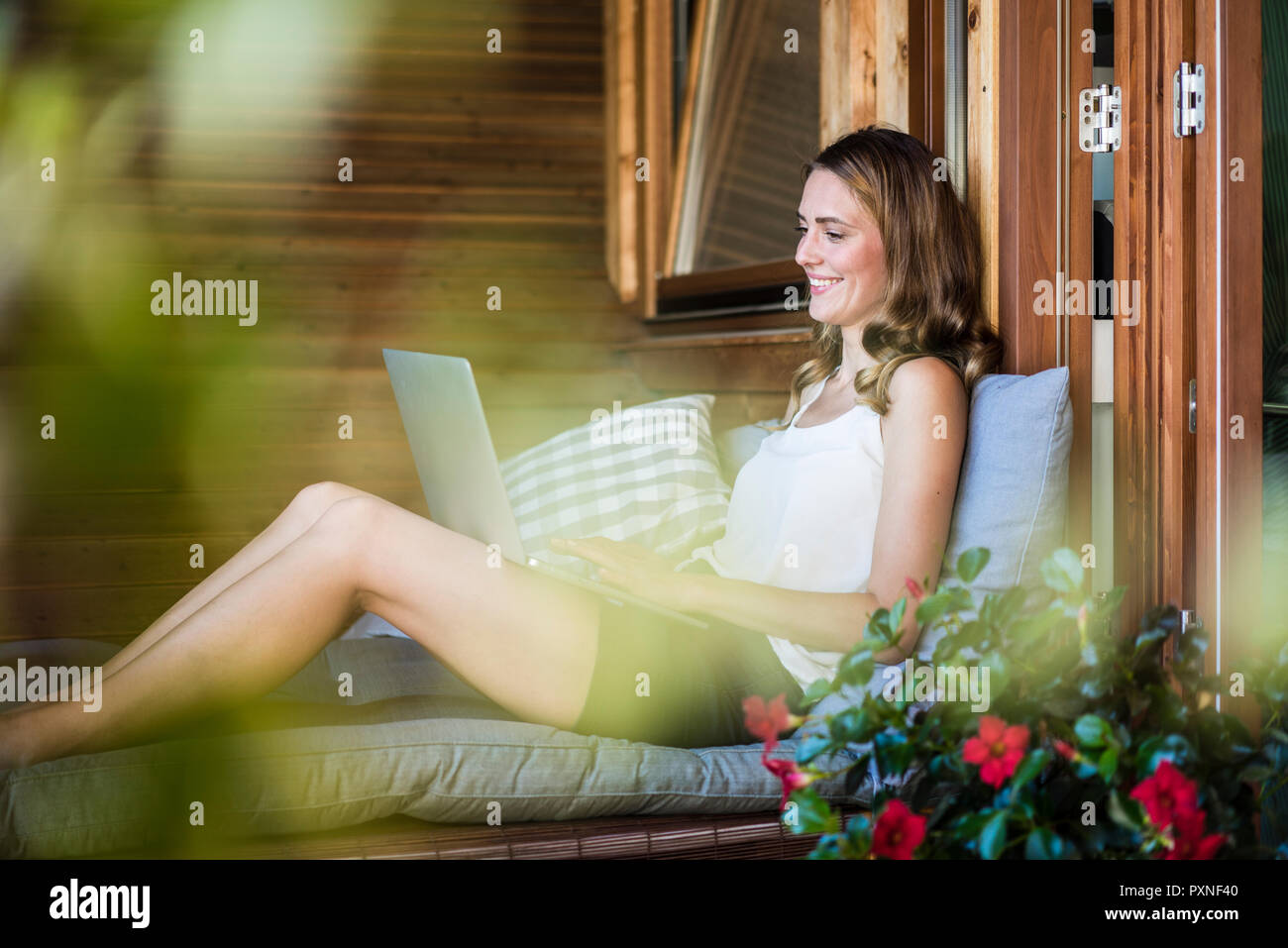 Smiling woman on balcony using laptop Stock Photo