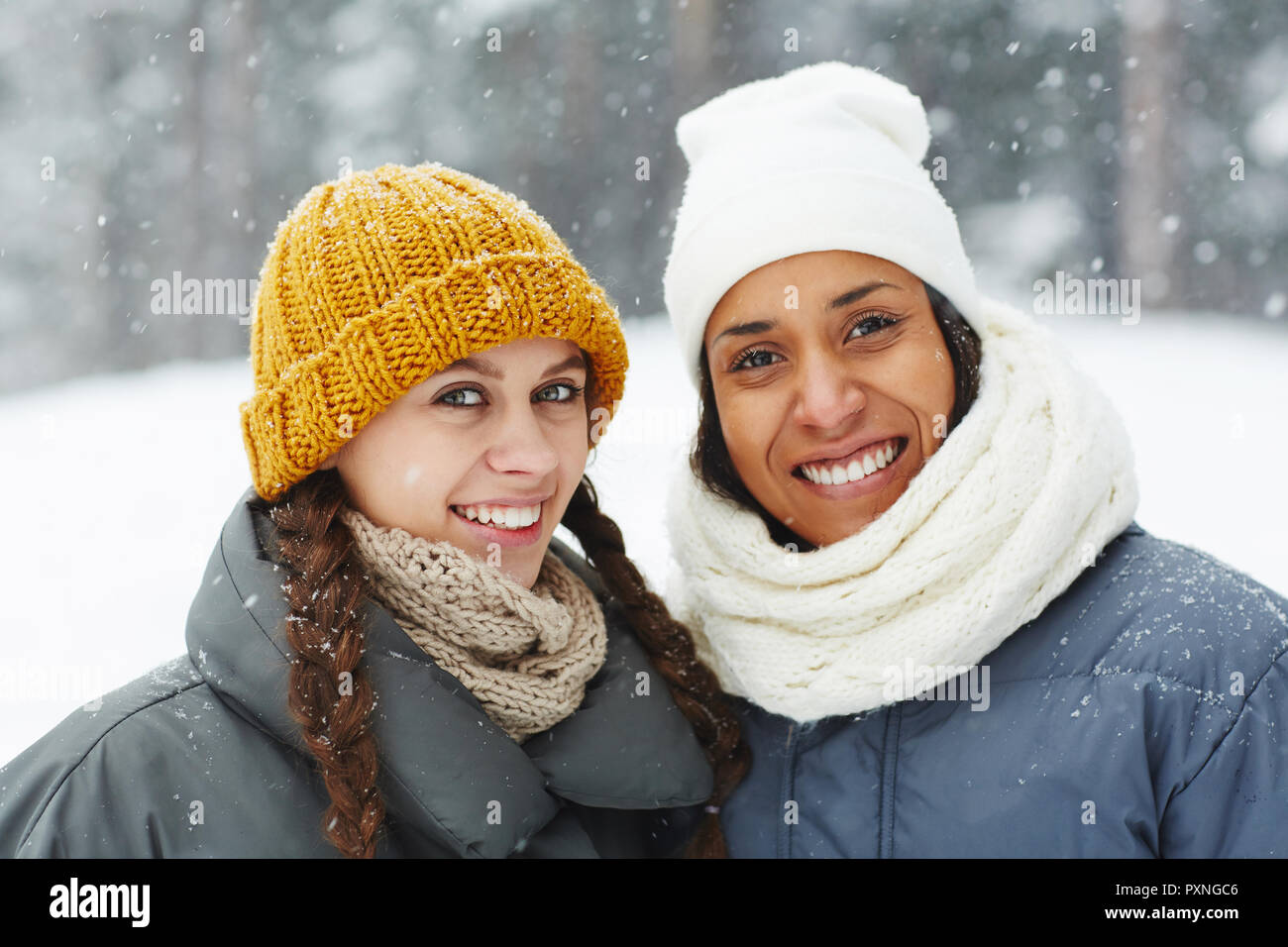 Smiling pretty multi-ethnic girls in stylish hats looking at camera and ...