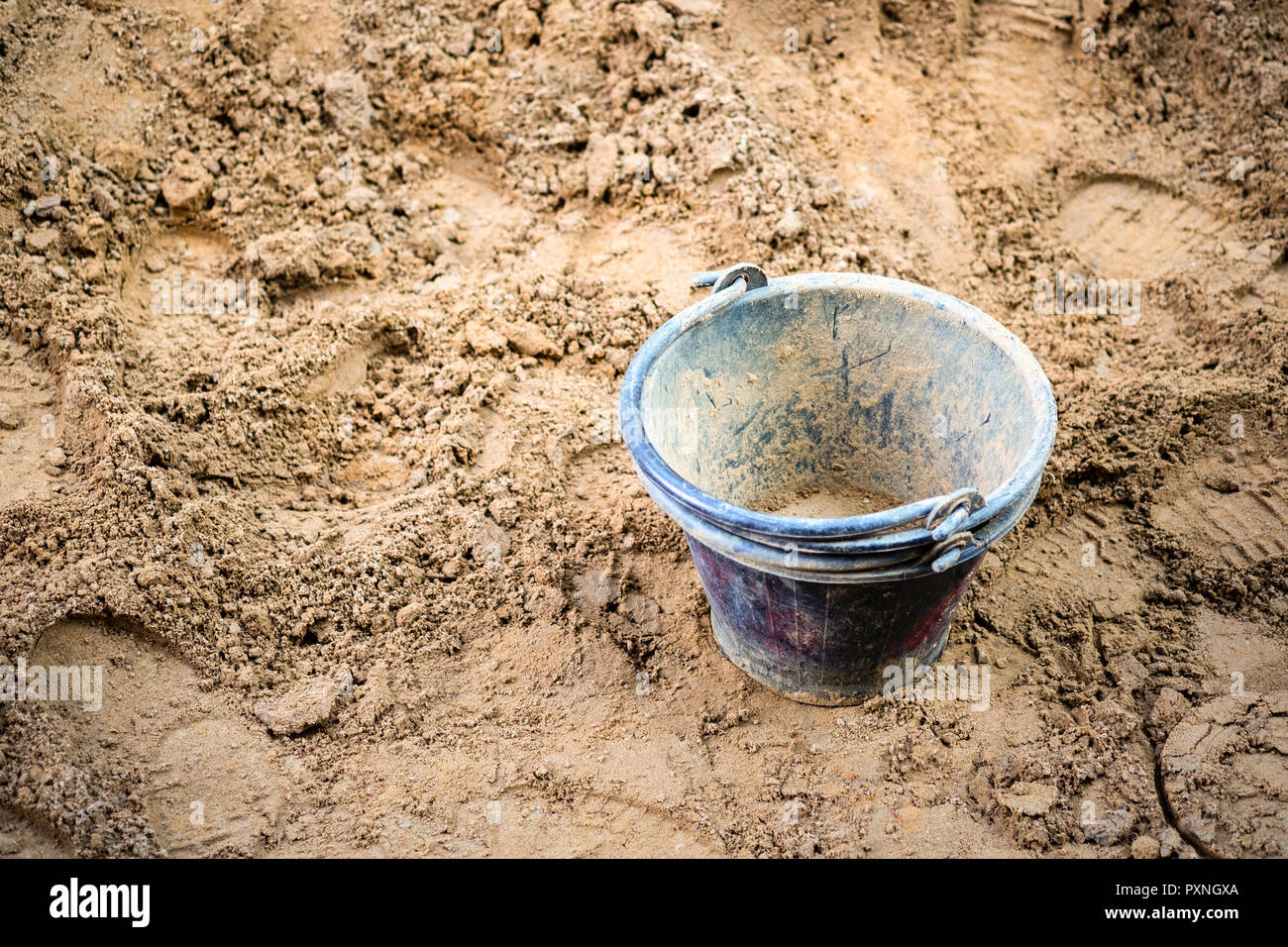Construction site bucket in black colour placed on a pile of sand