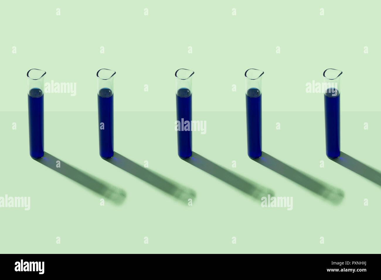 Row of test tubes with blue liquid, green background Stock Photo