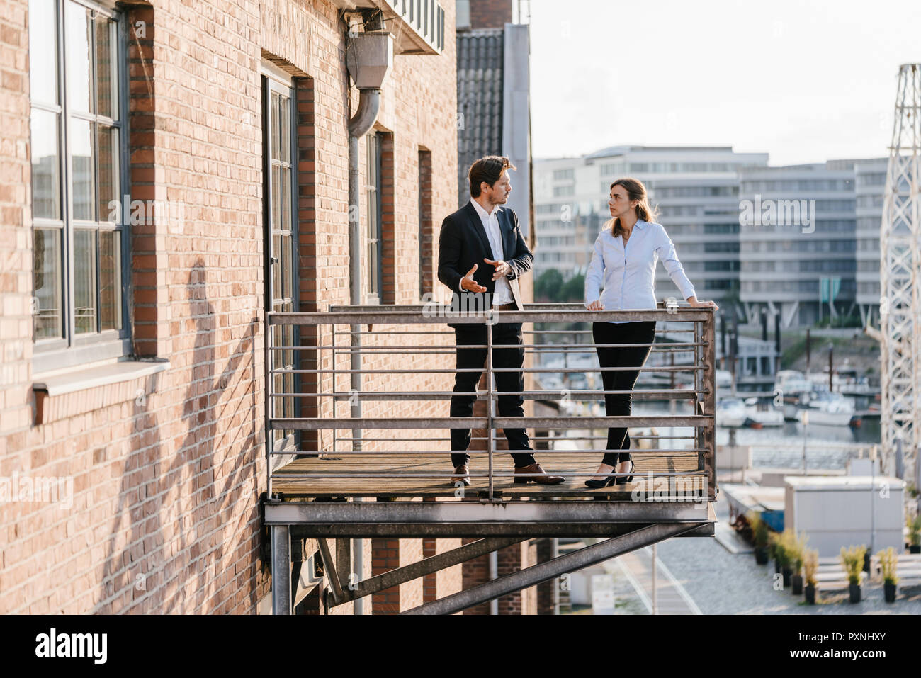 Business people standing on balcony, discussing Stock Photo - Alamy