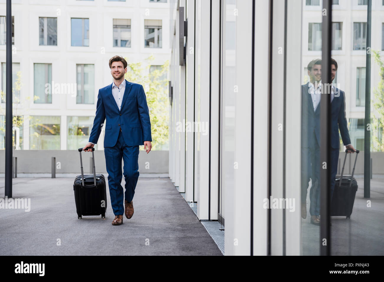 Smiling businessman with baggage in the city on the move Stock Photo