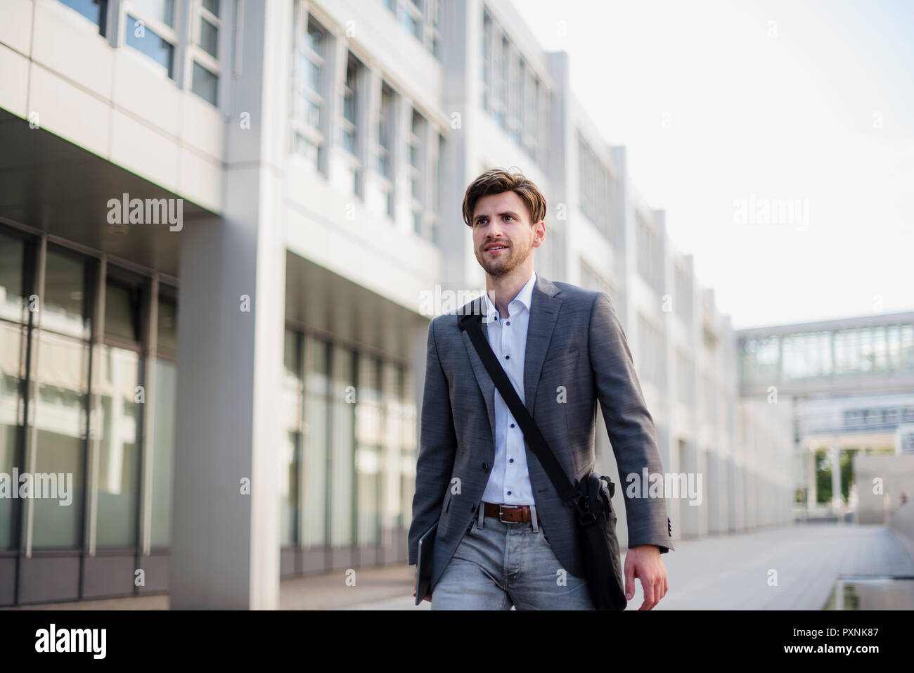 Smiling businessman with crossbody bag in the city on the move Stock Photo