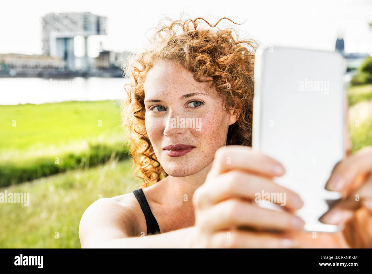 Germany, Cologne, portrait of freckled young woman taking selfie with cell phone Stock Photo