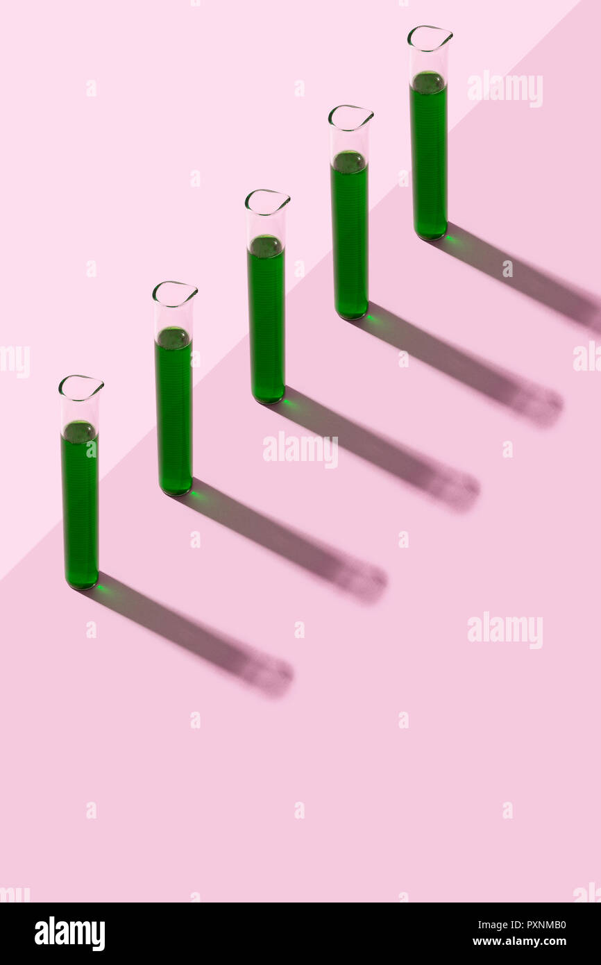 Row of test tubes with liquid, pink background Stock Photo