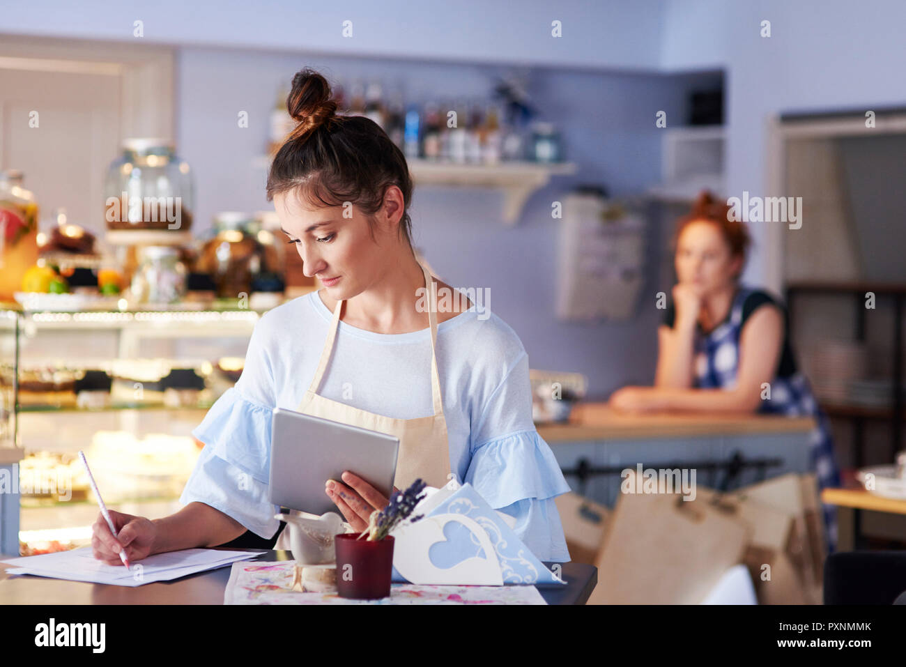 Woman working in a cafe taking notes Stock Photo