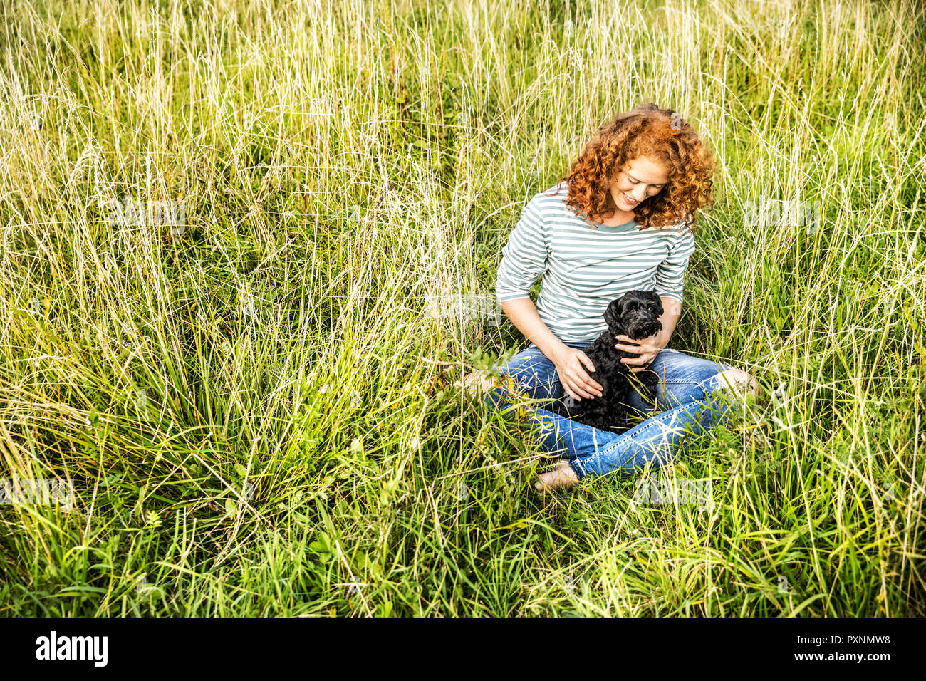 Young woman relaxing on a meadow with her dog Stock Photo