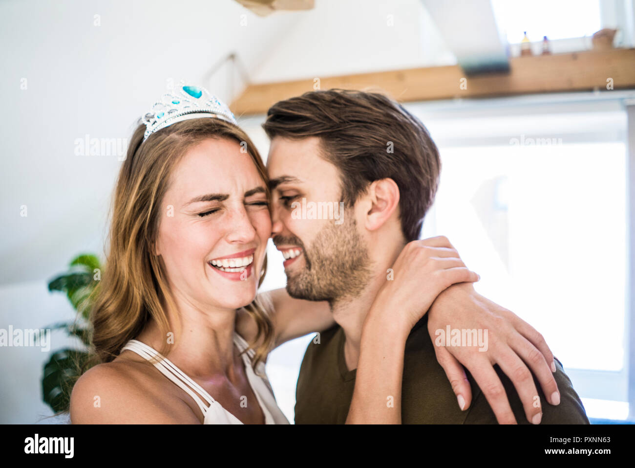 Happy couple at home with woman wearing tiara Stock Photo