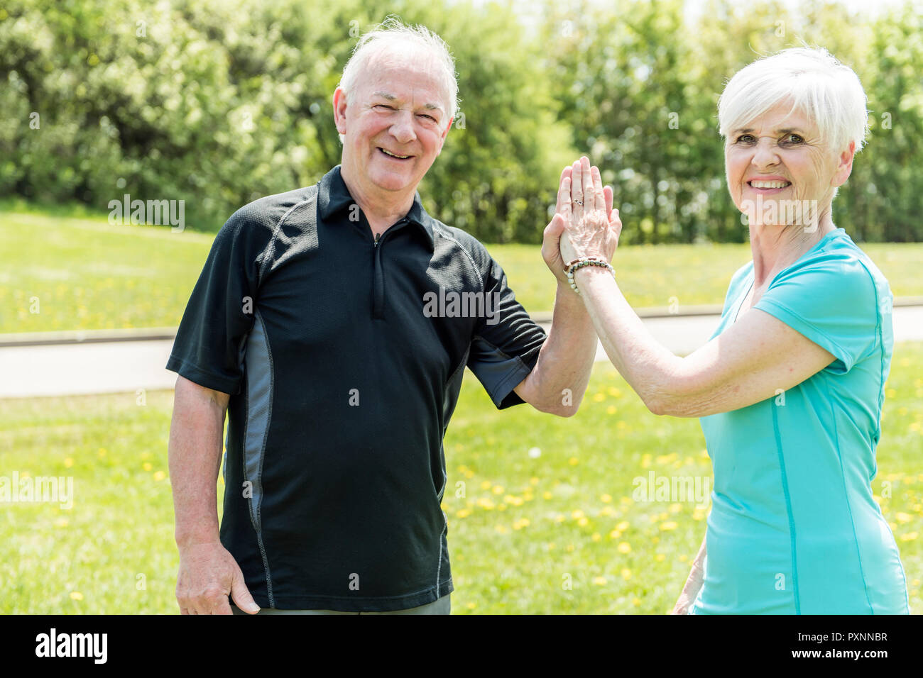 Senior couple running in park doing high five Stock Photo
