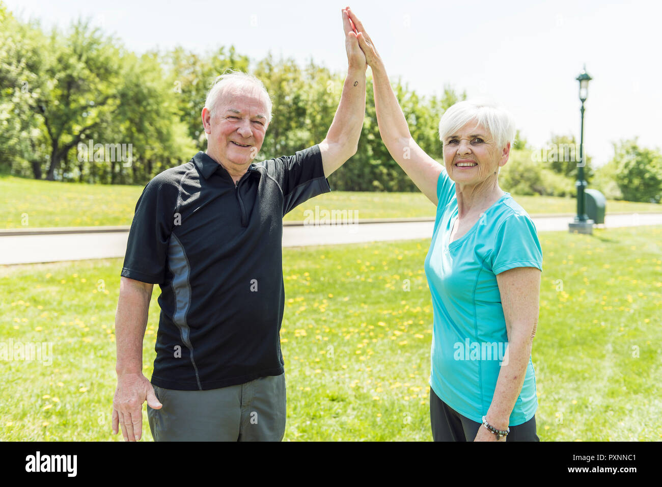 Senior couple running in park doing high five Stock Photo