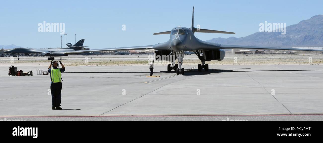 A B-1B Lancer parks, while another taxis down the runway during weapons integration at Nellis Air Force Base, Nev., June 14, 2017. In the final week of integration, the mission takes four days to review, prepare, plan and execute. To complete this three hour mission, 40 hours is invested by each participant. Stock Photo