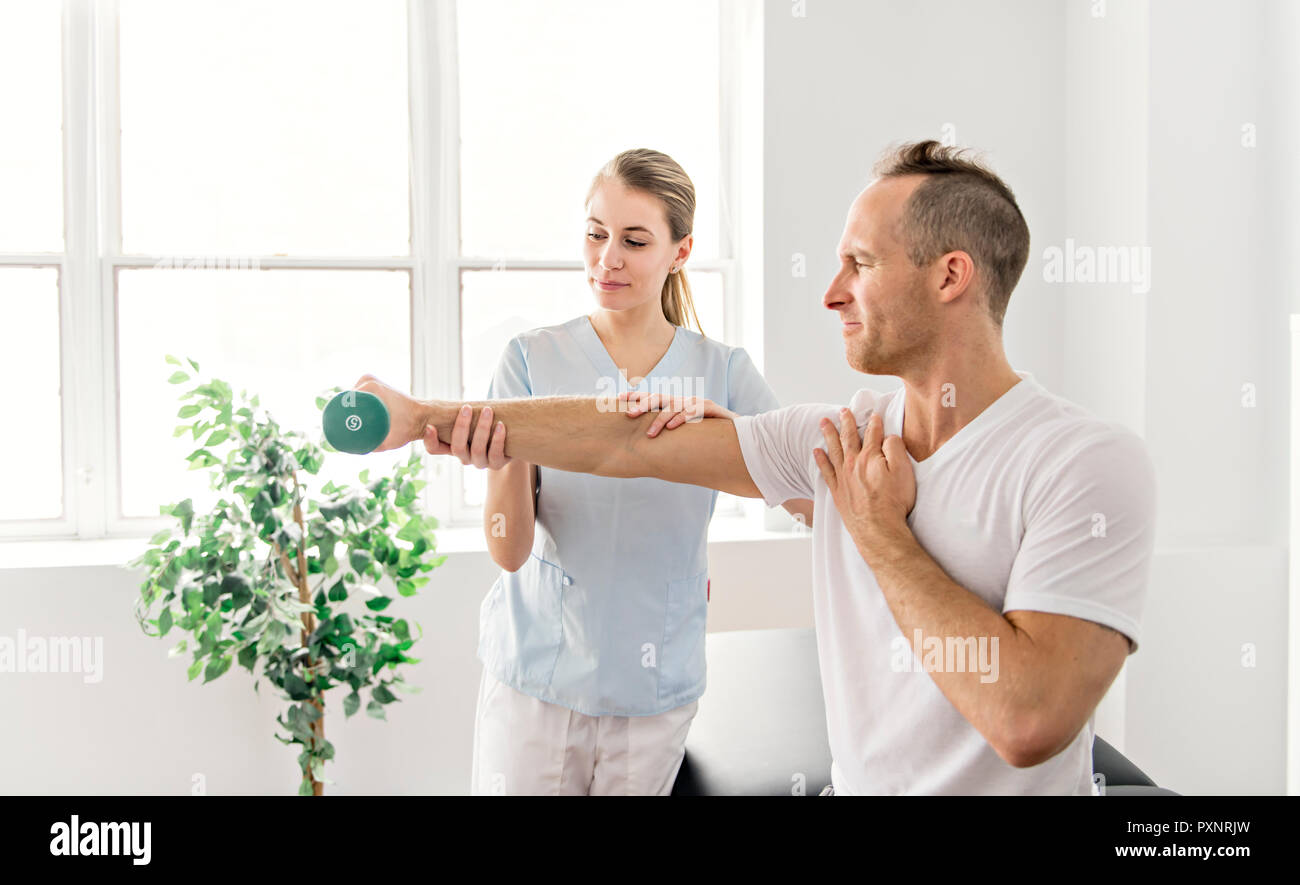 Patient at the physiotherapy doing physical exercises with his therapist Stock Photo