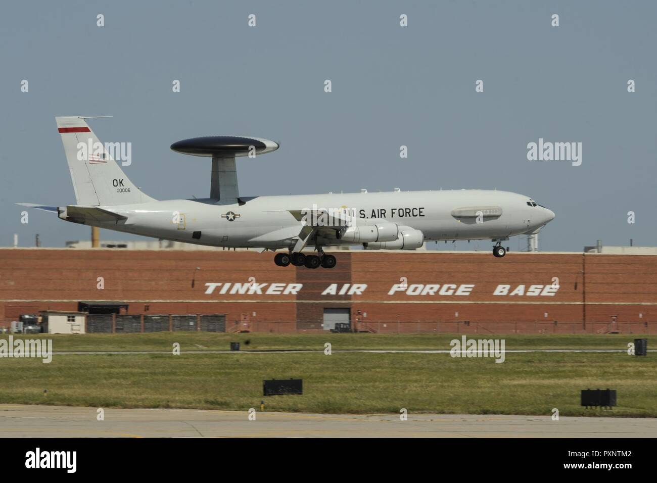 A Boeing E-3G Airborne Warning and Control System aircraft on final approach to land June 16, 2017, Tinker Air Force Base, Oklahoma. The large building behind the E-3 AWACS is building 3001, a former Douglas Aircraft manufacturing plant during World War II, now used by the Oklahoma City Air Logistics Complex and its parent organization the Air Force Sustainment Center. The E-3 is operated by the 552nd Air Control Wing, Air Combat Command, from Tinker AFB where heavy maintenance of the E-3 airframe and engines is also conducted by the OC-ALC. Stock Photo