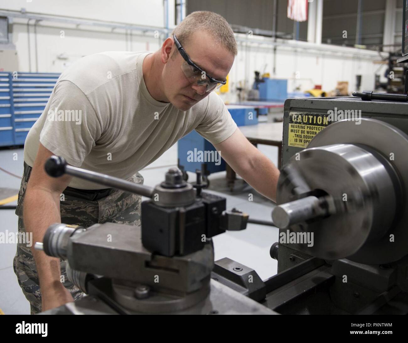 U.S. Air Force Staff Andrew Walker, a fabrication specialist with the 379th Expeditionary Maintenance Squadron uses a manual lathe to create a cylindrical part at Al Udeid Air Base, Qatar, June 5, 2017. Walker is part of a team of machinists and welders which are trained on a wide range of manual and computer numerical controlled machines to manufacture and repair aircraft components and support equipment. Stock Photo