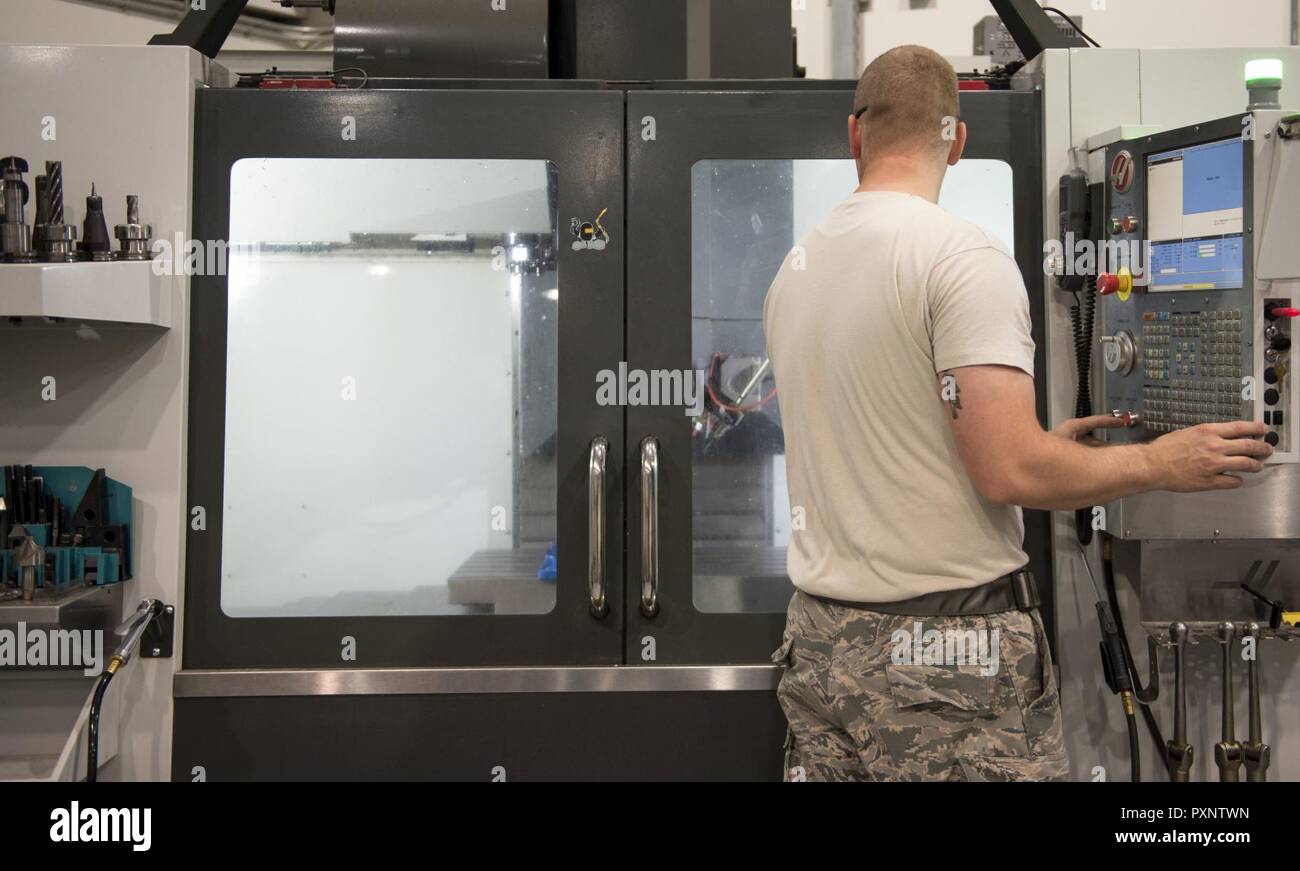 U.S. Air Force Staff Andrew Walker, a fabrication specialist with the 379th Expeditionary Maintenance Squadron uses a computer numerical control machine at Al Udeid Air Base, Qatar, June 5, 2017. The CNC allows Walker and other machinists to increase the speed of the manufacturing and reduce the wait time for new aircraft parts. Stock Photo