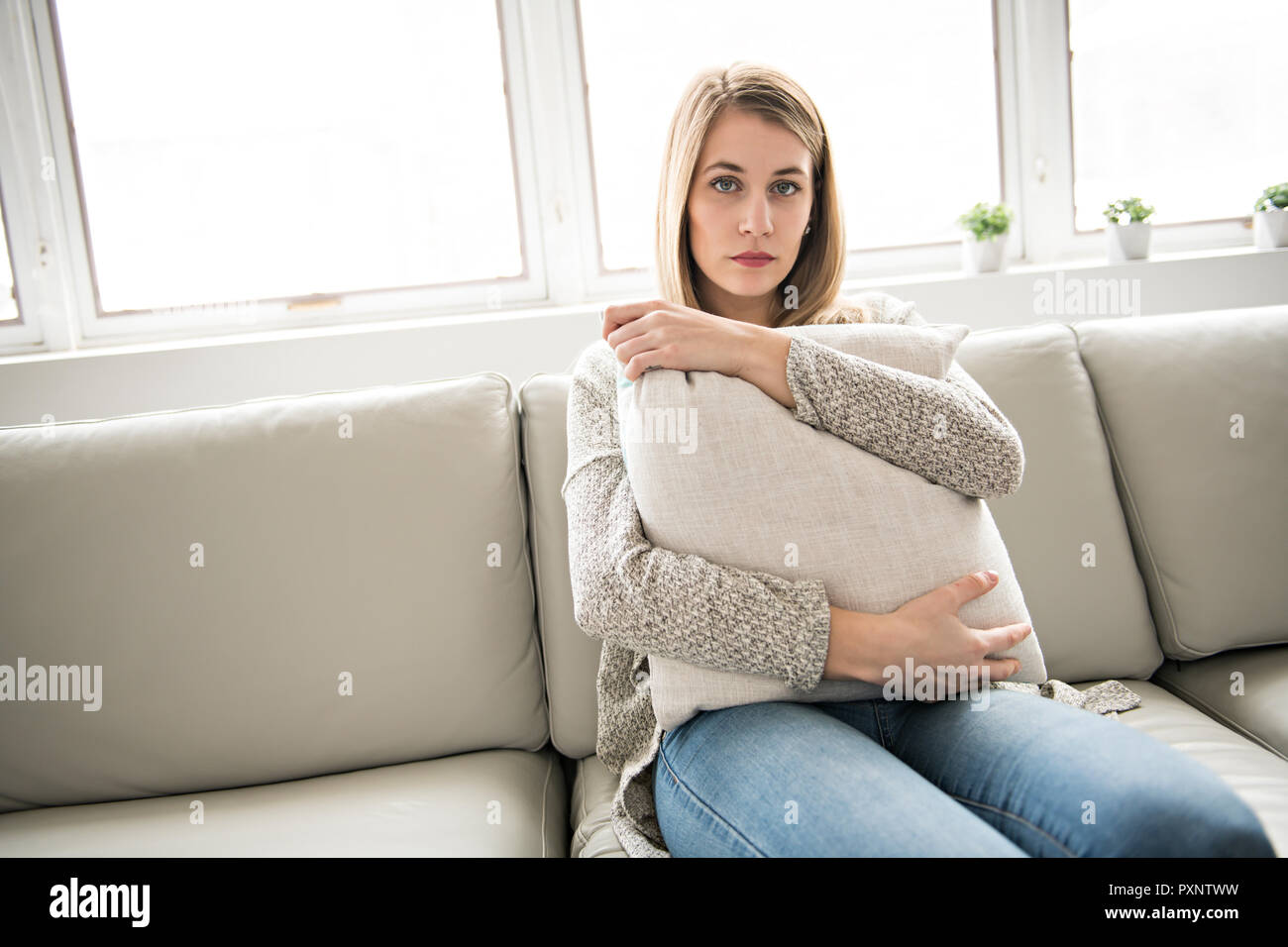 Depressed young woman on sofa at home Stock Photo