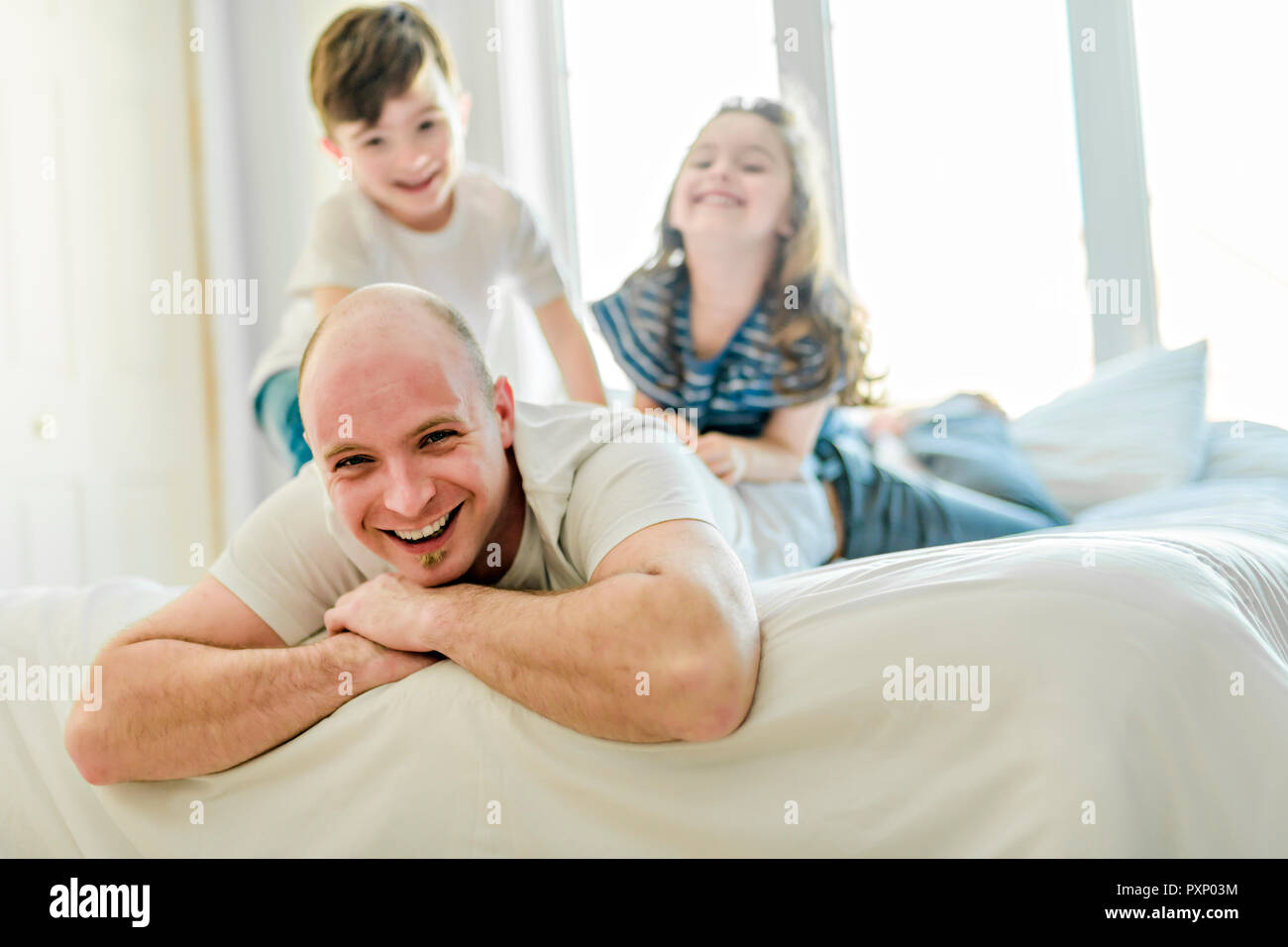 Happy father two kids having fun together on a bed stock photo alamy