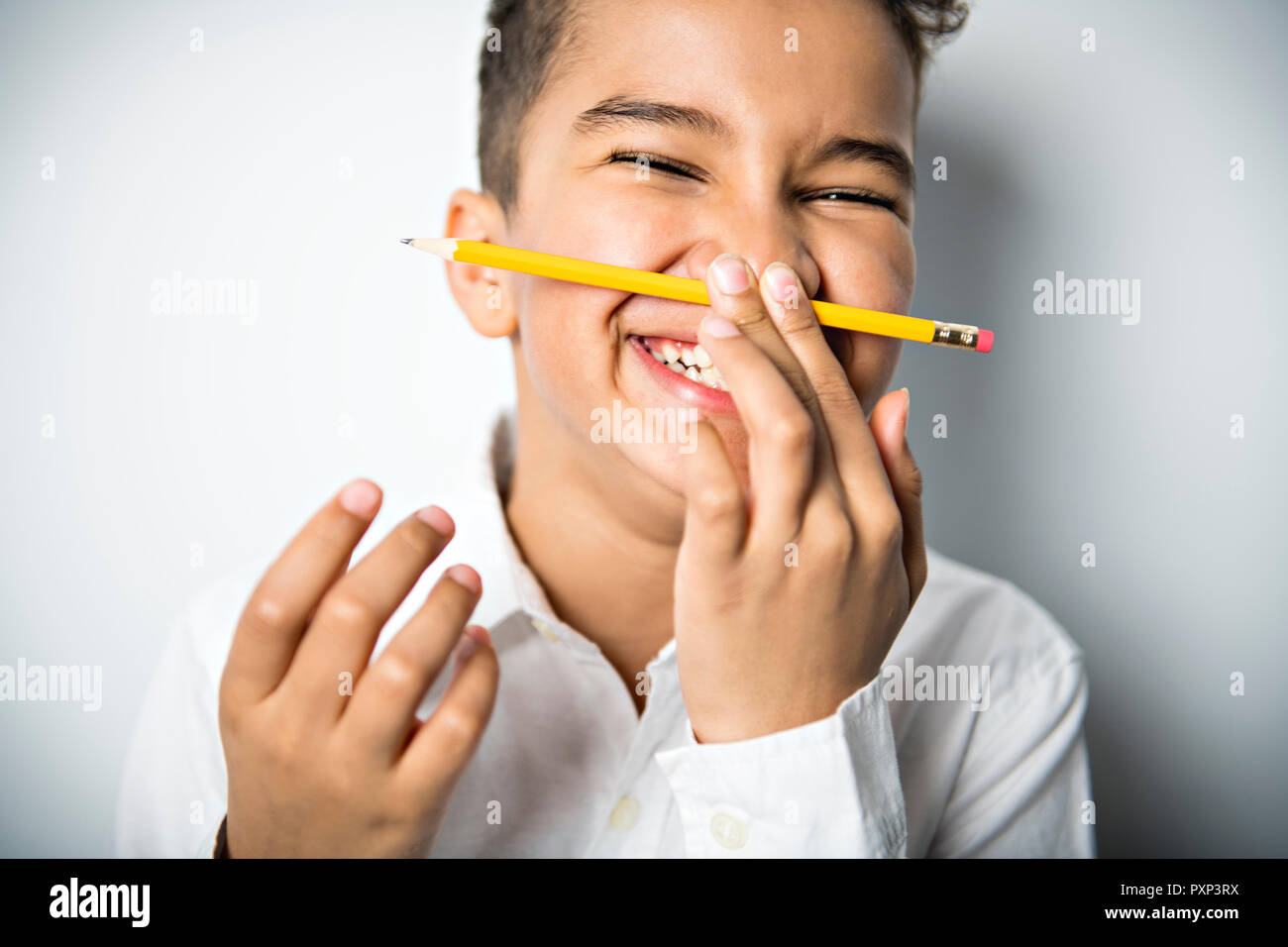 Black boy holding school pensil and take it on his nose Stock Photo