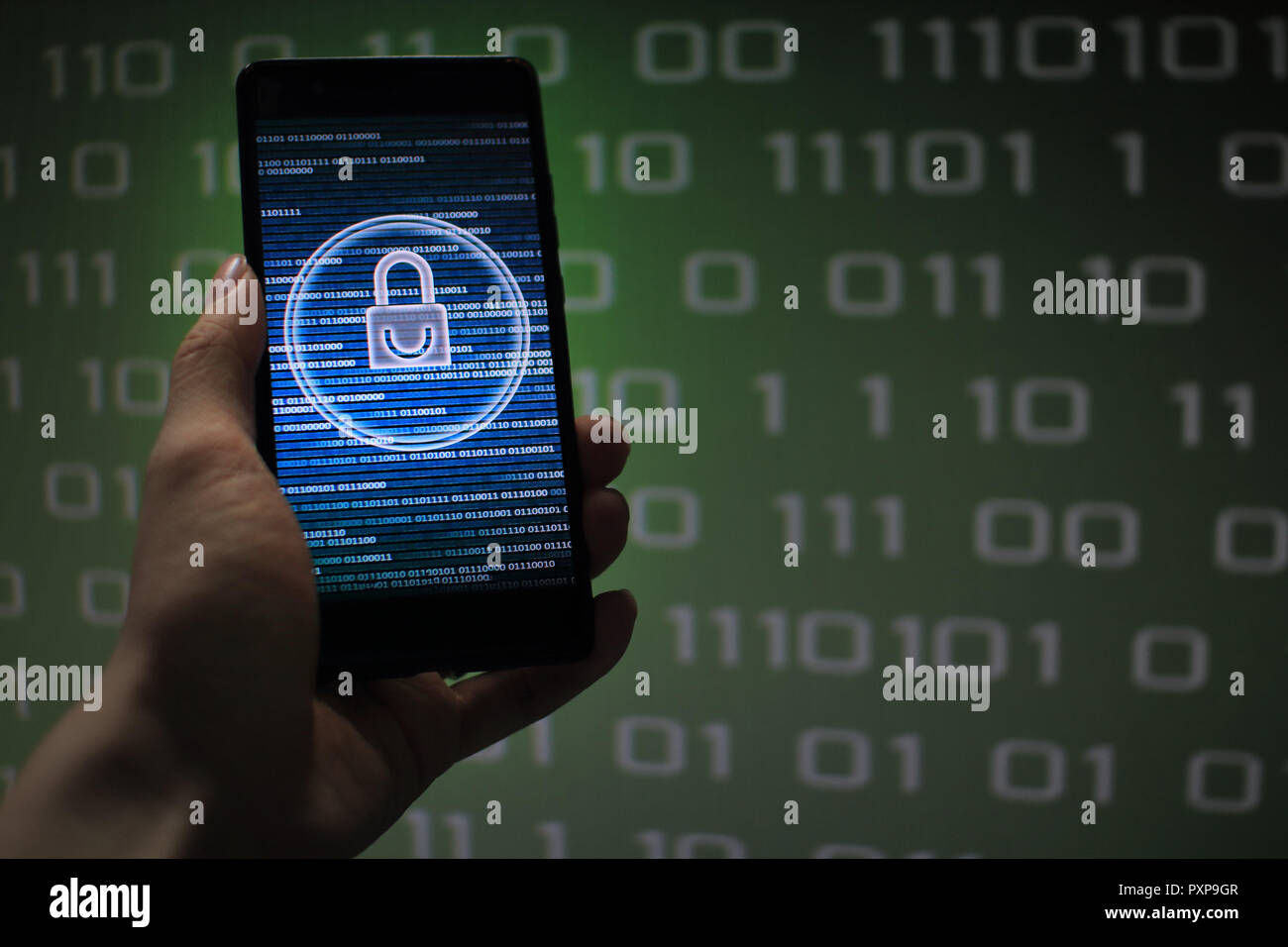 protected in stream of data flow. padlock icon symbolize security and Green binary code computer data in the background. hand holding mobile phone. Stock Photo