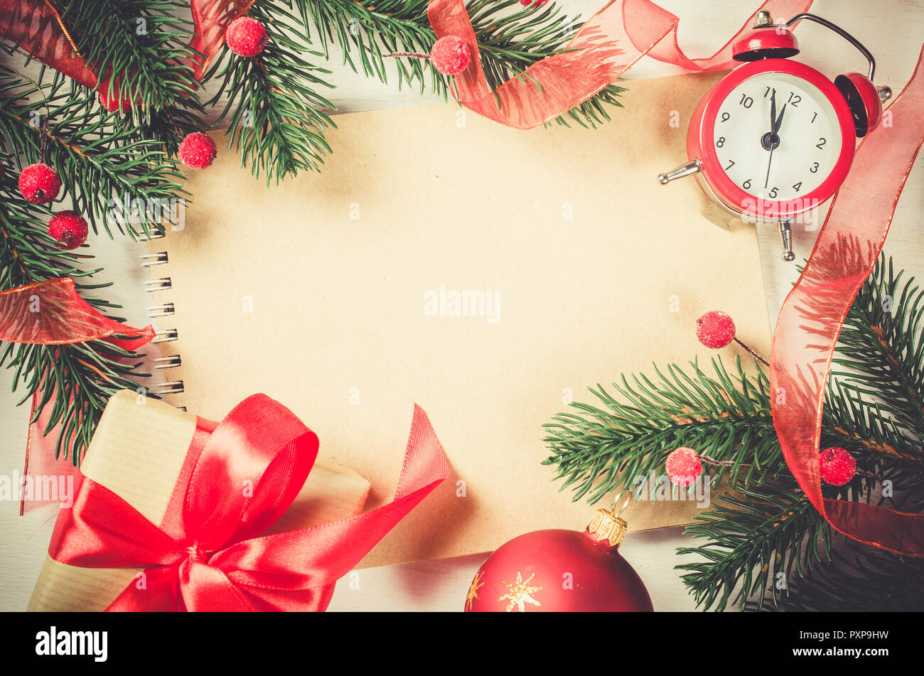 Vintage Christmas background with empty notebook and clock, branches christmas tree and xmas decoration. Toned image. Top view. Selective Focus. Stock Photo