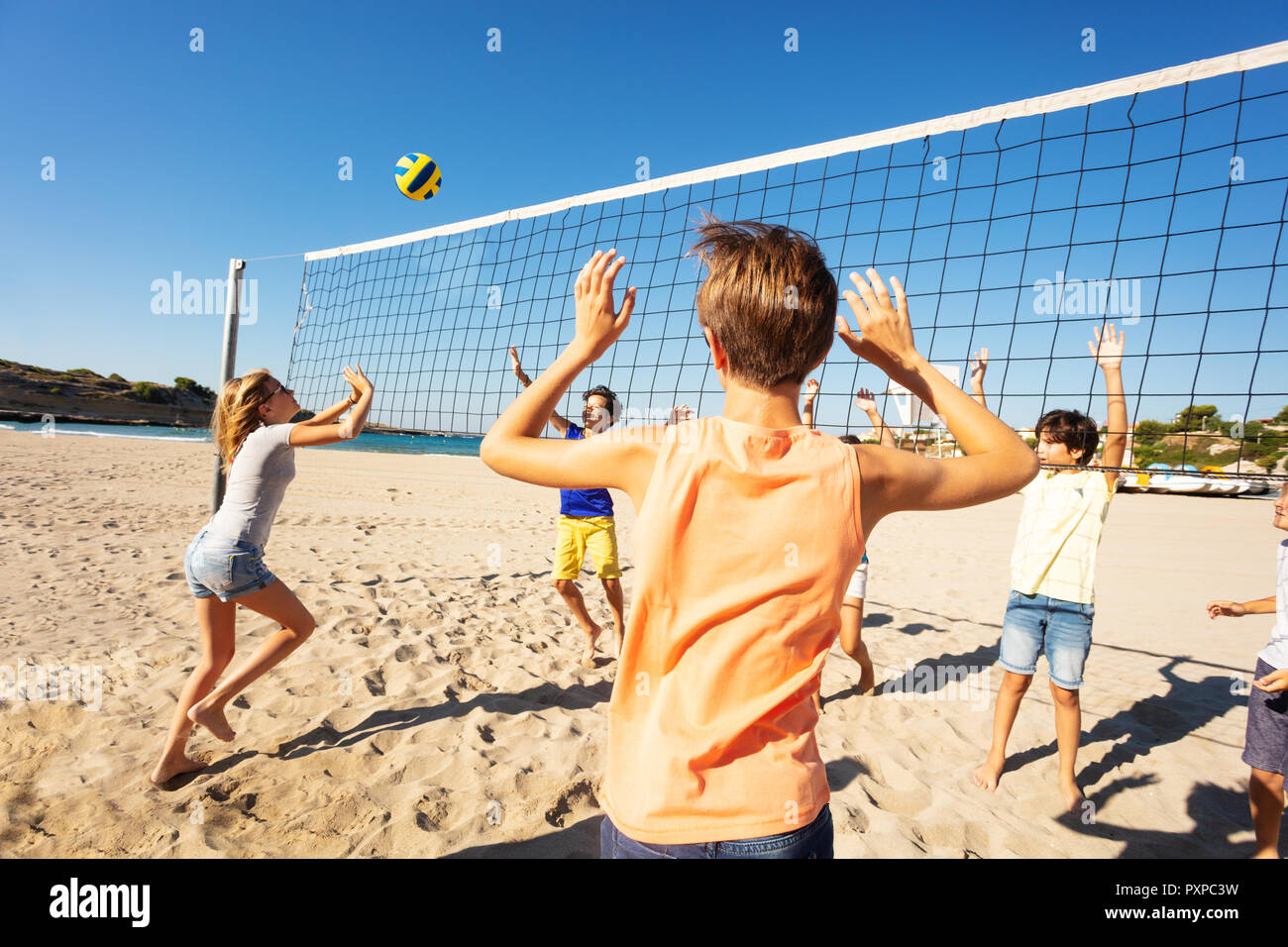 Sporty teenage girl passing the ball over the net during beach volleyball  match at sunny day Stock Photo - Alamy