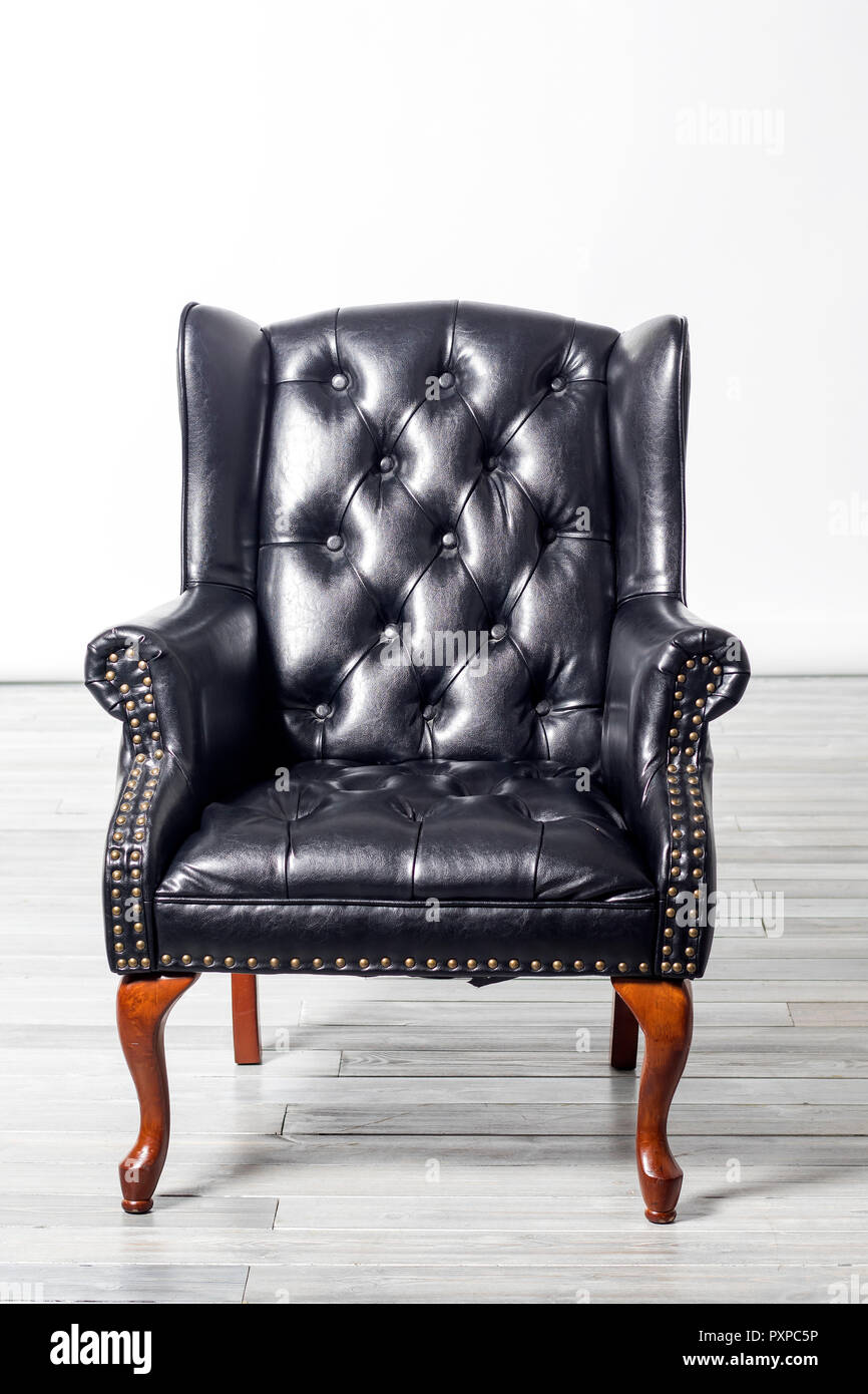 the old antique black leather wing arm chair Stock Photo Alamy