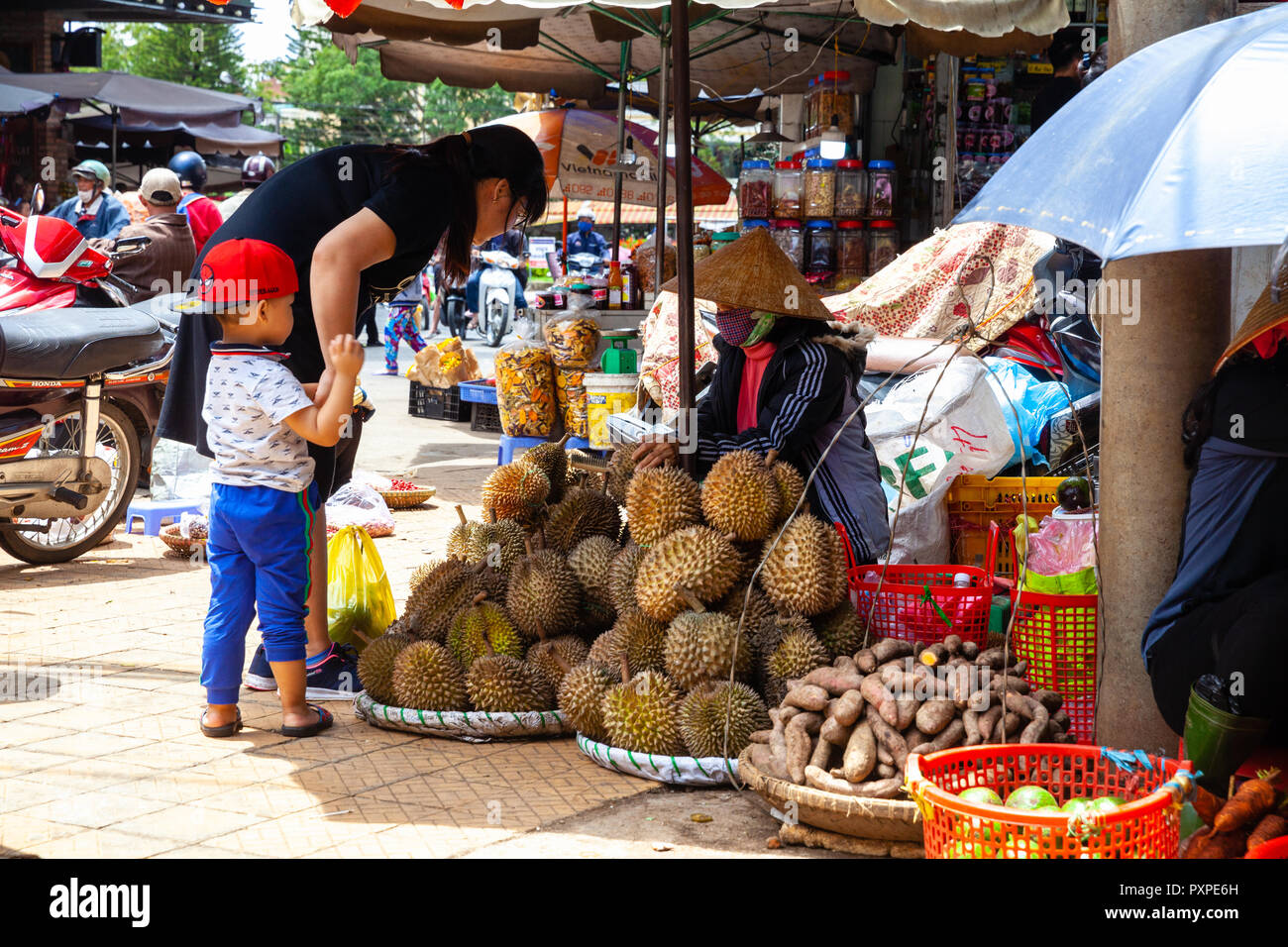 DA LAT, VIETNAM - SEPTEMBER 23: A Vietnamese woman with a child buys durian on the street market on September 23, 2018 in Da Lat, Vietnam. Stock Photo