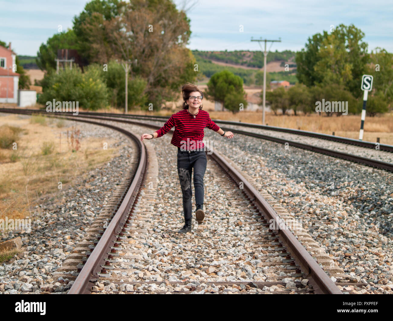A teenage girl jumping on the train tracks. Concept of freedom and joy