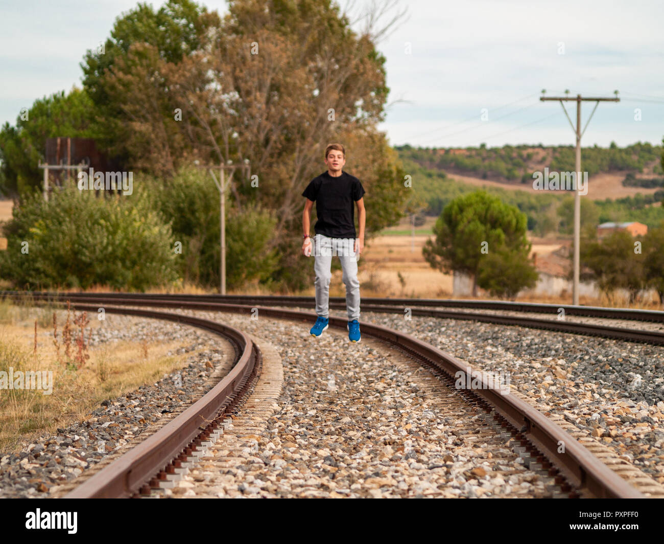 A teenage boy jumping on the train tracks. Concept of freedom and joy
