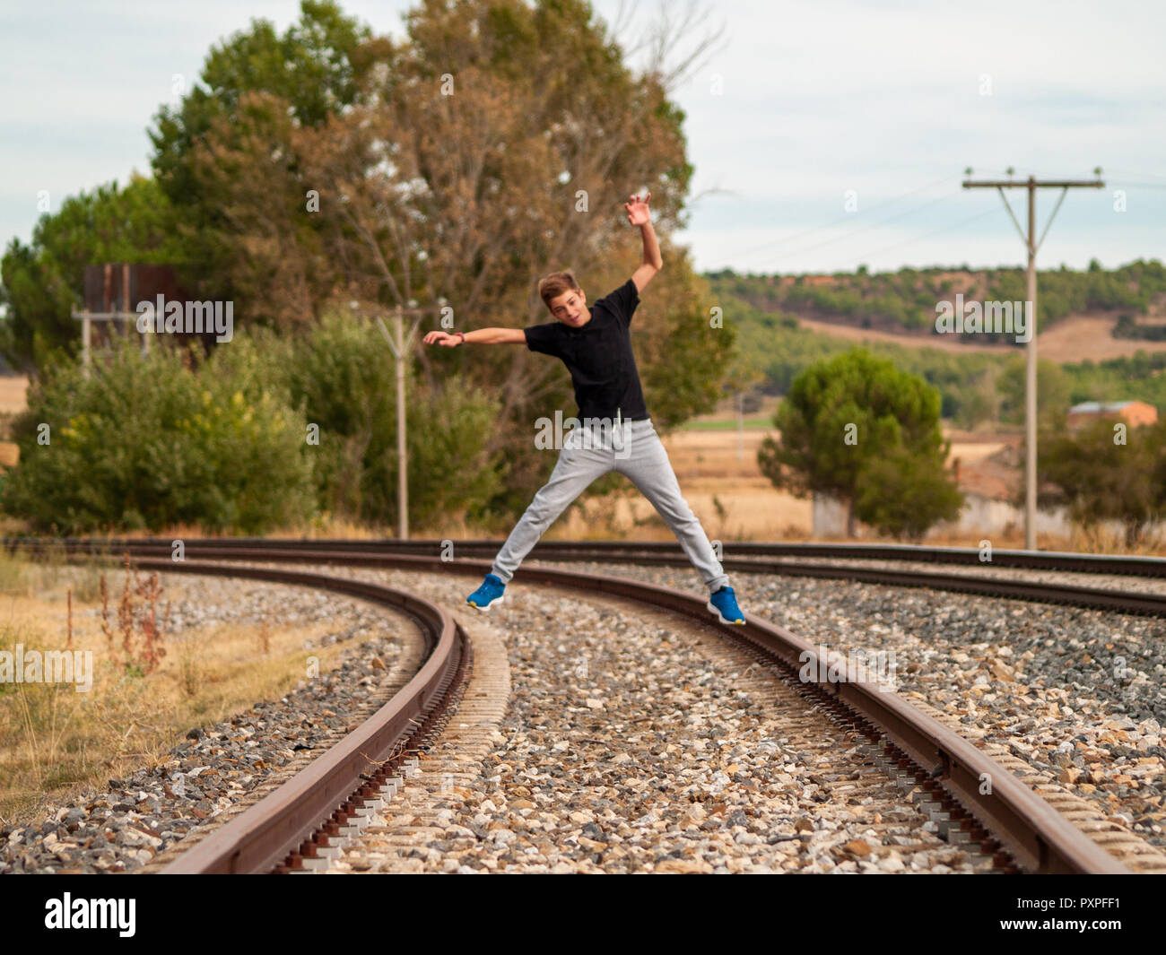 A teenage boy jumping on the train tracks. Concept of freedom and joy