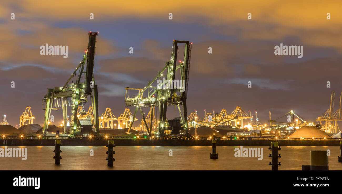 Industrial landscape with Harbor quay and two loading cranes at night in Europoort Maasvlakte Port of Rotterdam Netherlands Stock Photo