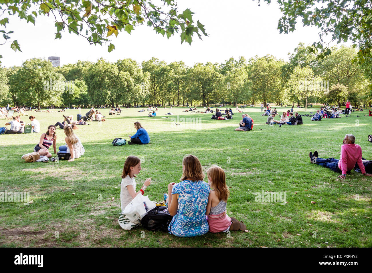 London England,UK,Green Park,Ritz Corner,Royal Parks,lawn,outdoors,green space,sitting on grass,woman female women,girl girls,kid kids child children Stock Photo