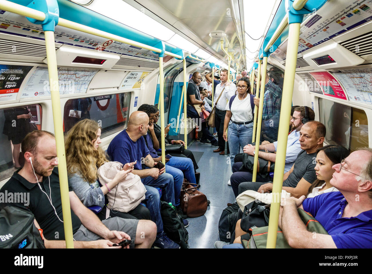 London England,UK,underground subway tube,train,carriage,inside interior,commuters,passenger passengers rider riders,man men male,woman female women,B Stock Photo