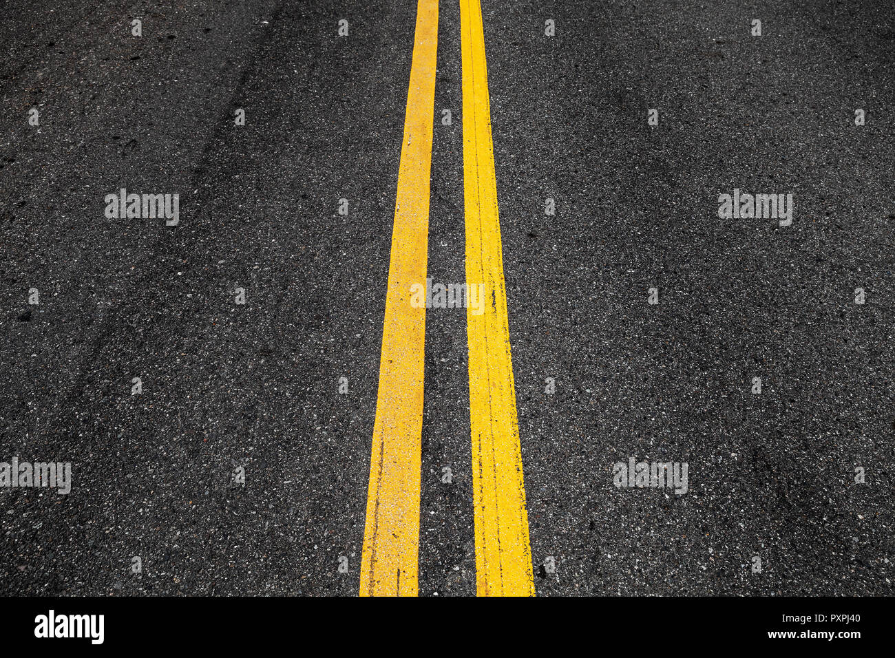 Yellow double dividing lines, highway road marking on dark asphalt