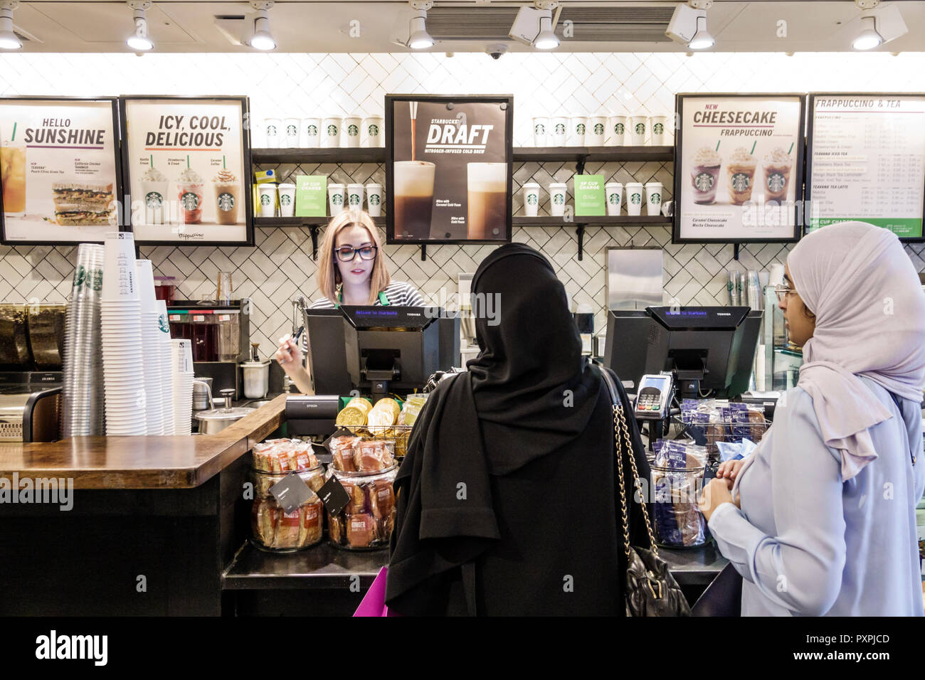 London England,UK,Soho Carnaby Street,Starbucks Coffee,cafe coffeehouse,counter,woman female women,cashier,customer,Muslim,hijab,Muslim ethnic barista Stock Photo